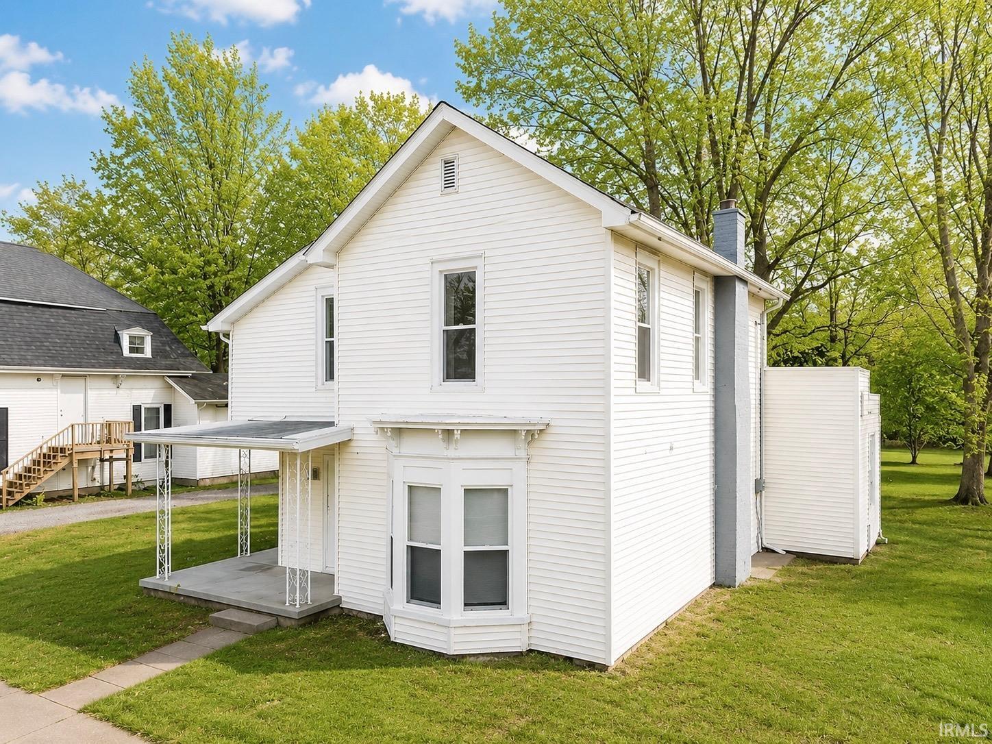 Rear view of property featuring a chimney and a lawn