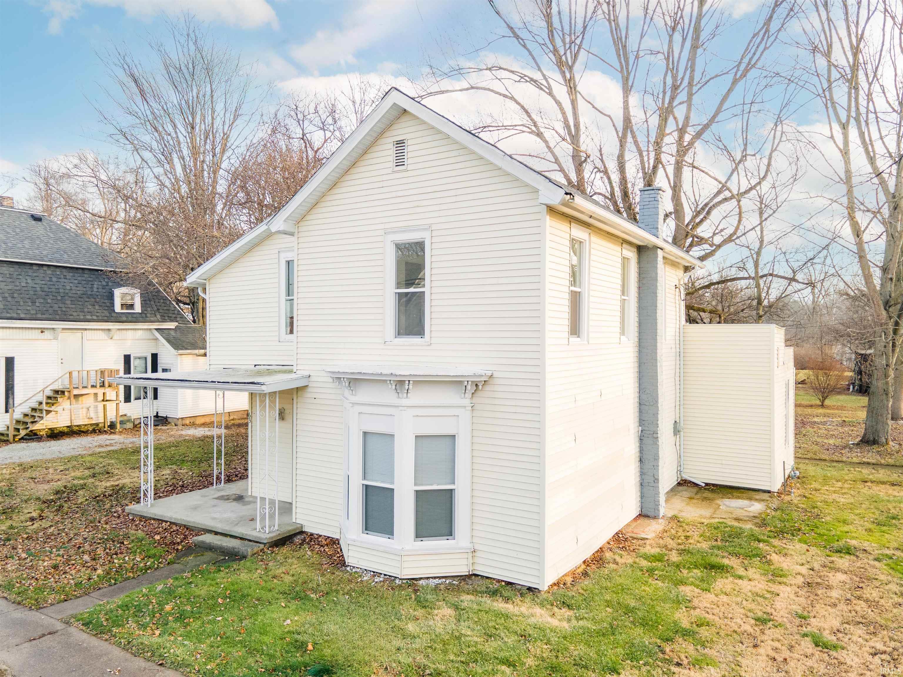 Rear view of property featuring a chimney and a lawn