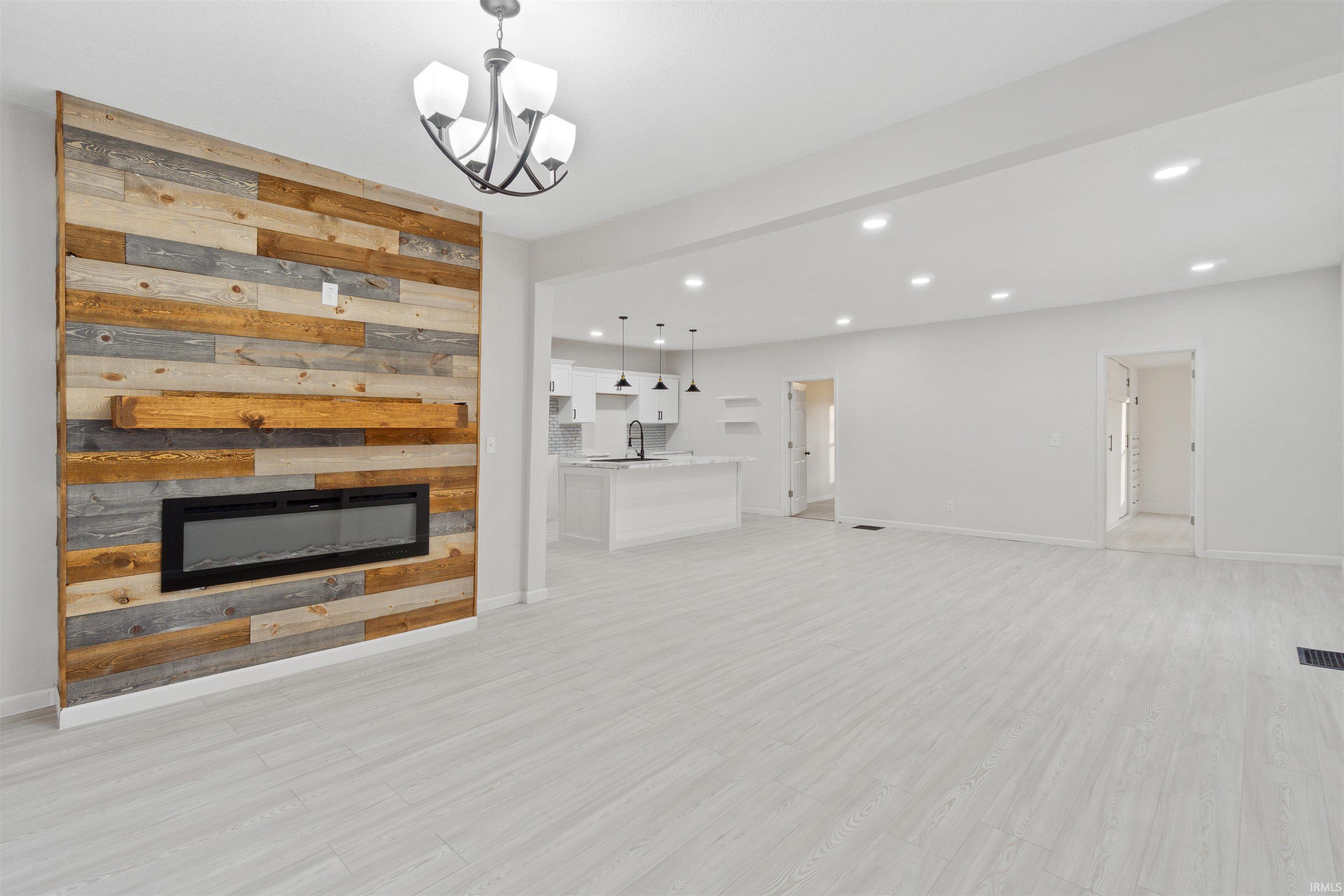 Unfurnished living room with recessed lighting, light wood-type flooring, and a chandelier