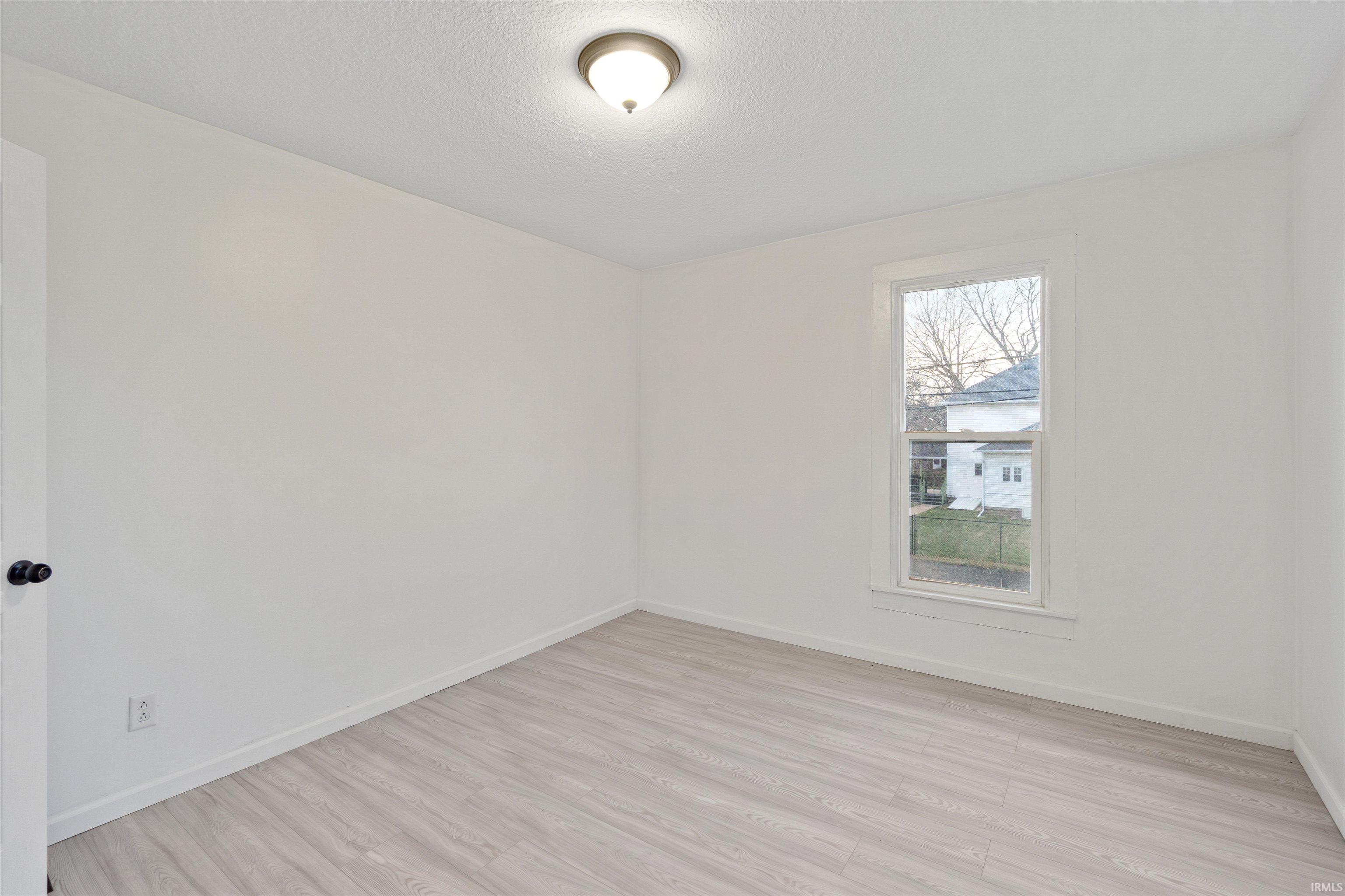 Spare room featuring light wood-style floors and a textured ceiling