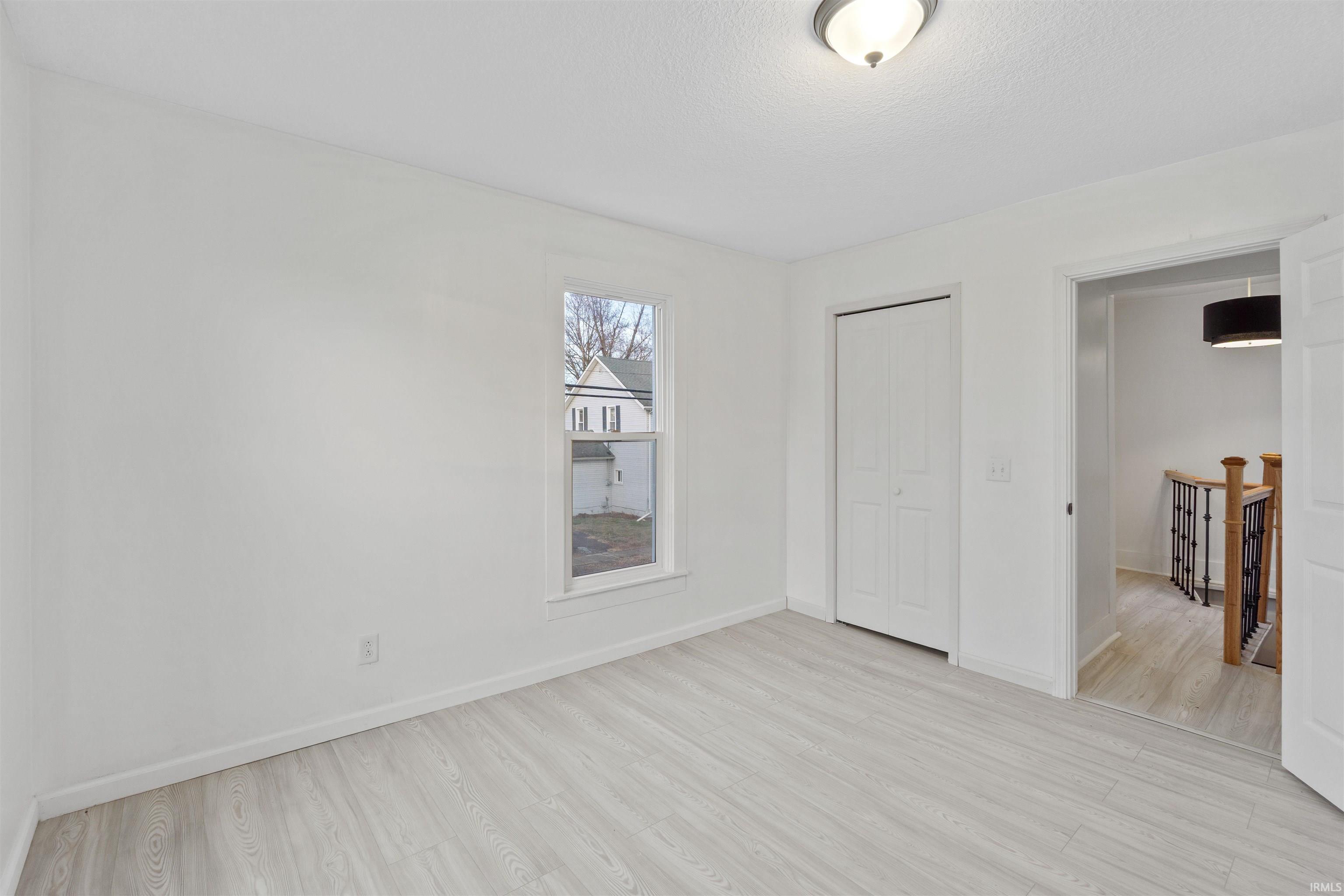 Unfurnished bedroom with light wood-style floors and a closet