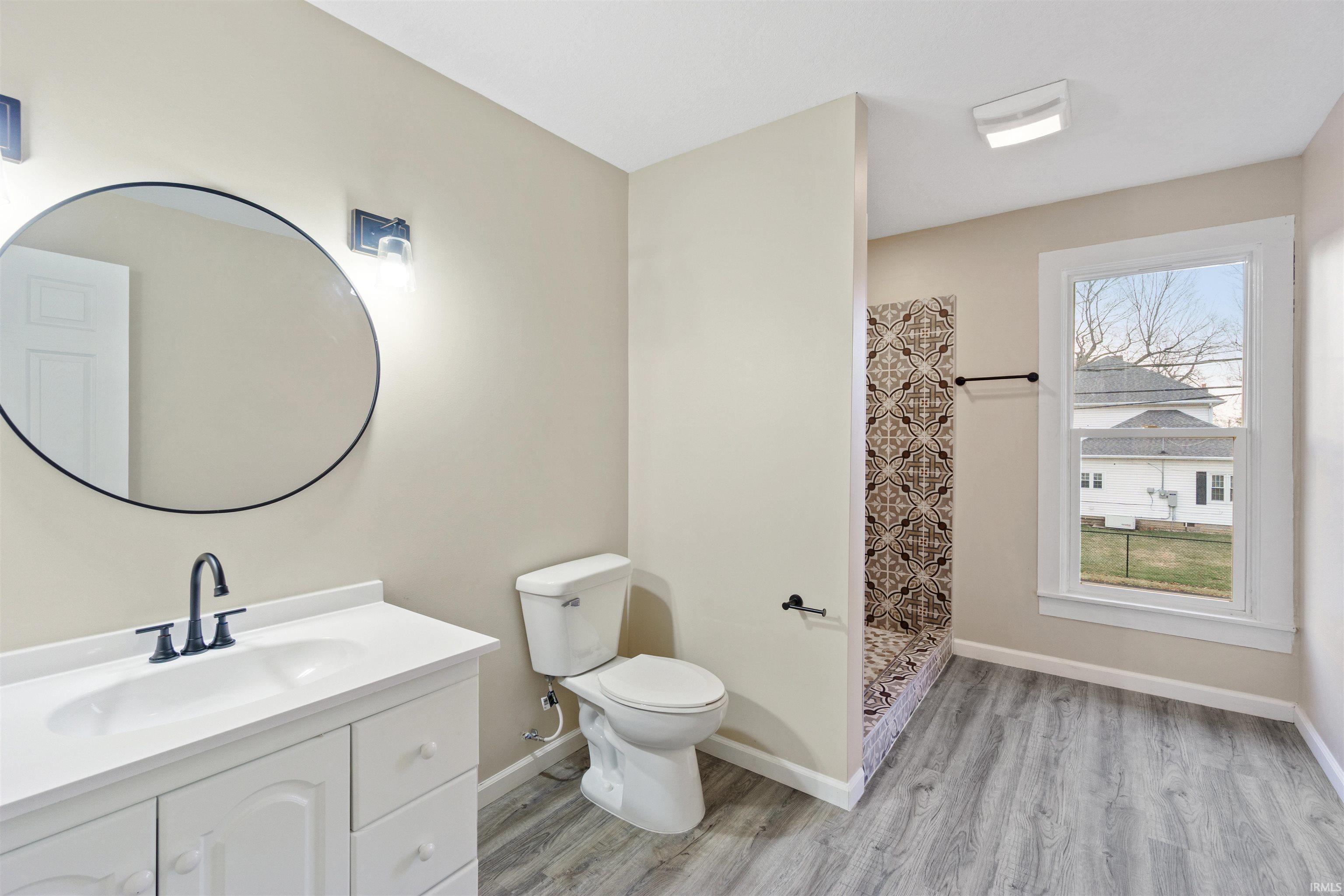 Full bath featuring vanity, a walk in shower, and light wood-type flooring