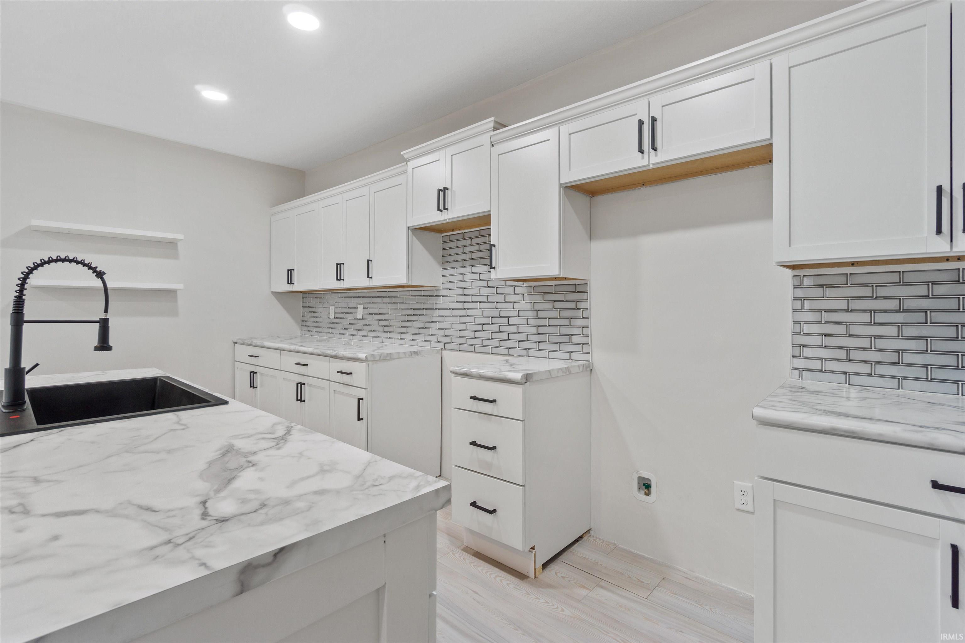 Kitchen featuring white cabinets, backsplash, recessed lighting, light wood-style floors, and light stone counters