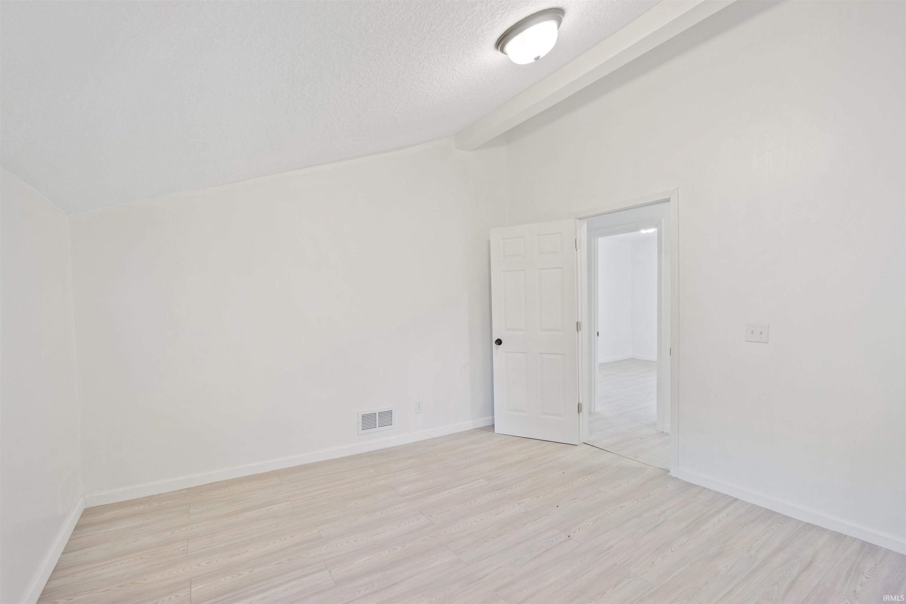 Unfurnished room with light wood-type flooring and a textured ceiling