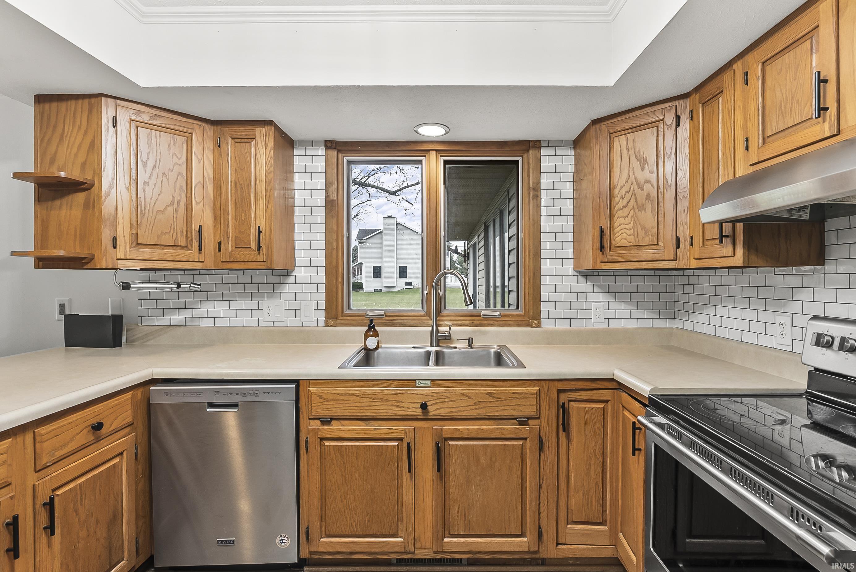 Kitchen featuring appliances with stainless steel finishes, brown cabinets, light countertops, and backsplash