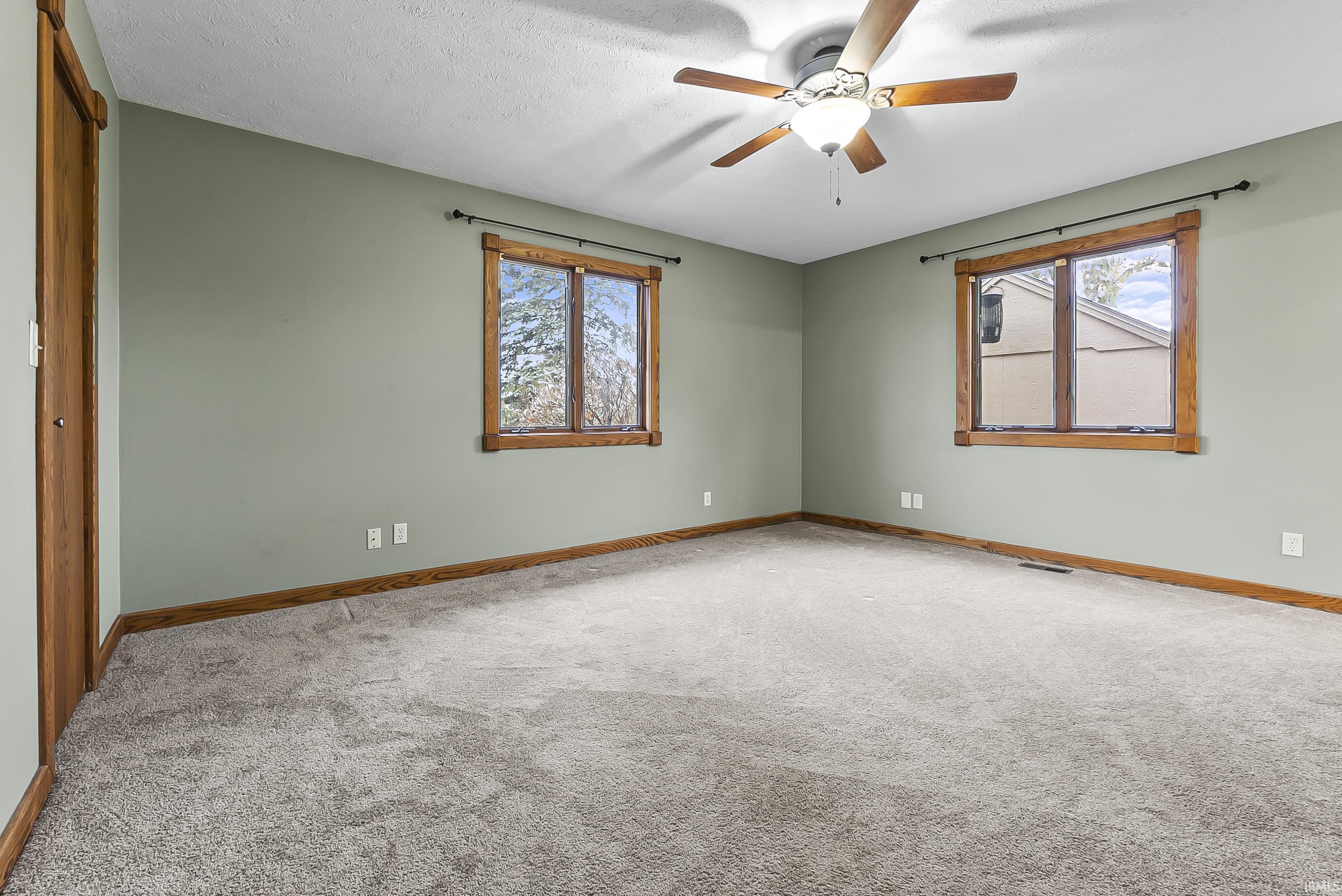 Carpeted empty room with a textured ceiling and ceiling fan