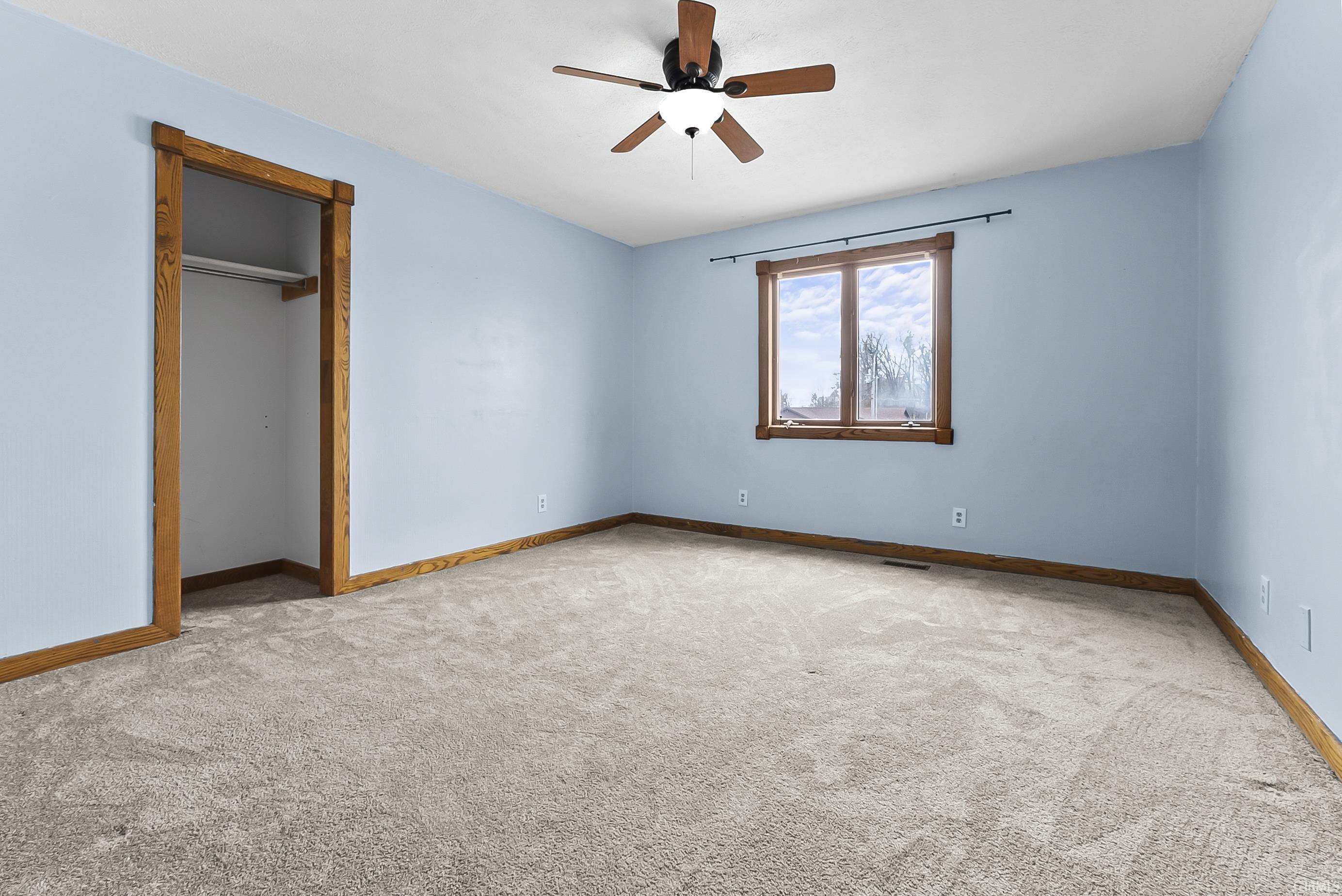 Unfurnished bedroom featuring light colored carpet, ceiling fan, and a closet