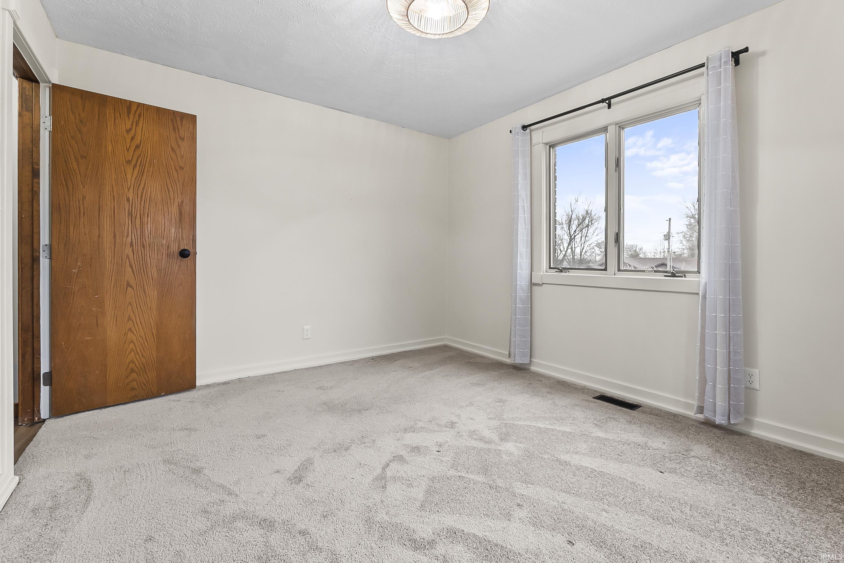 Empty room with light carpet and baseboards
