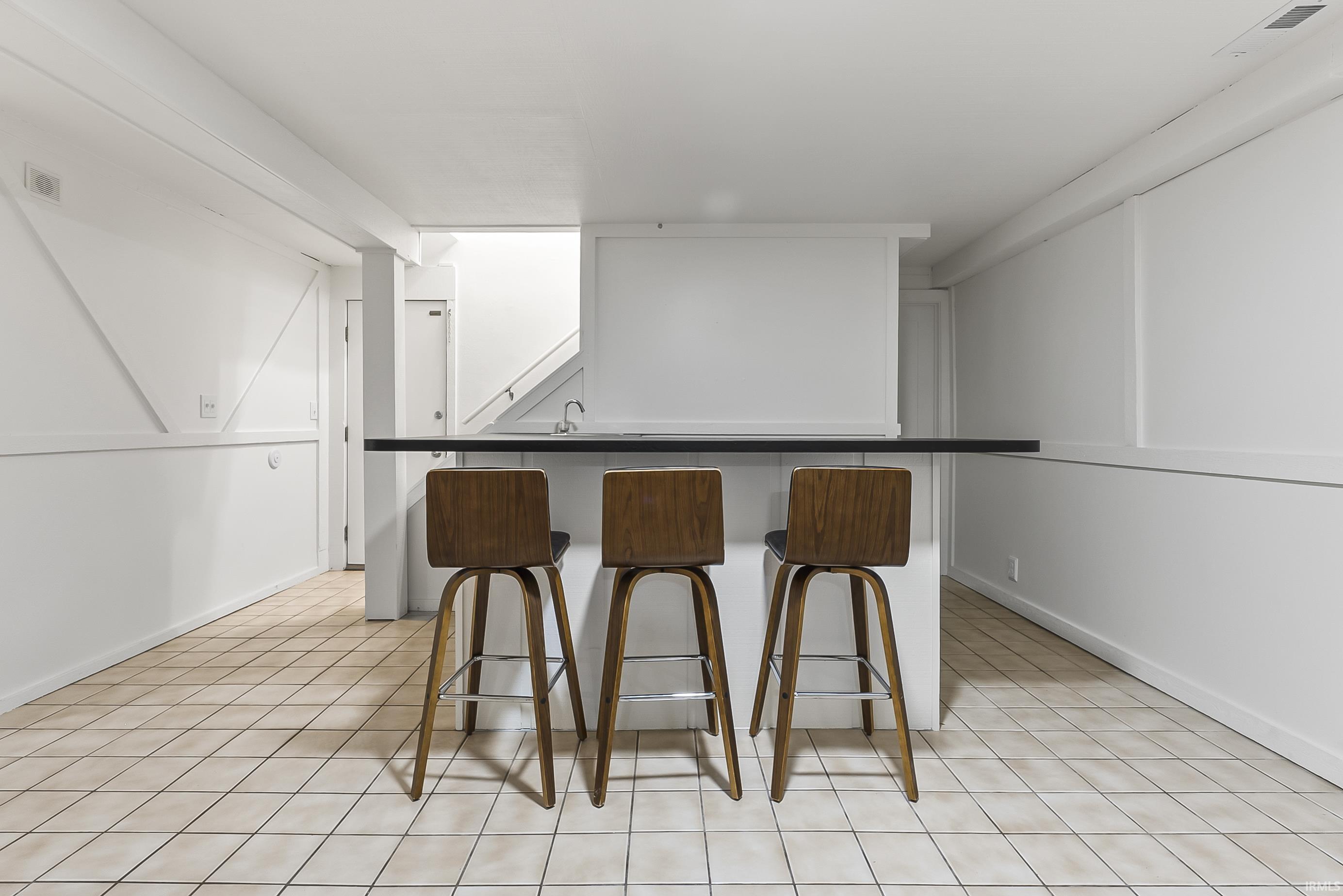 Kitchen featuring dark countertops, a kitchen breakfast bar, and light tile patterned floors