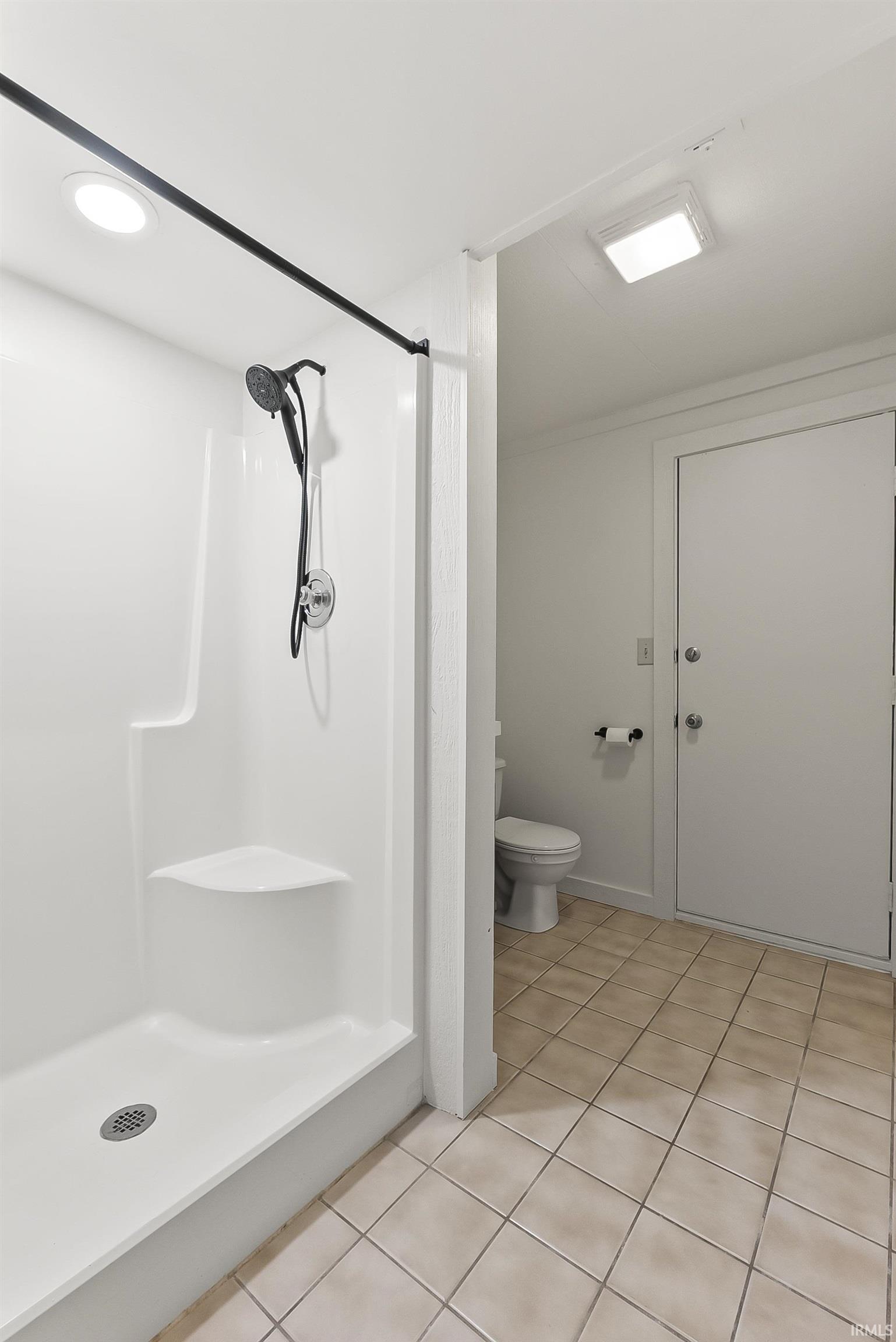 Bathroom with a stall shower and light tile patterned floors