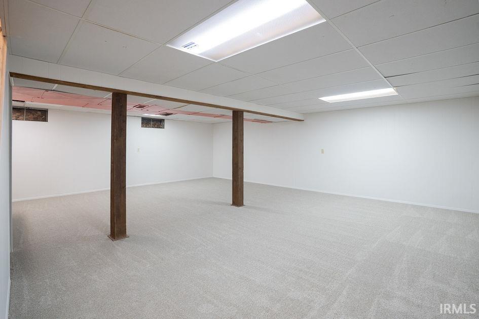 Finished below grade area with light carpet and a paneled ceiling