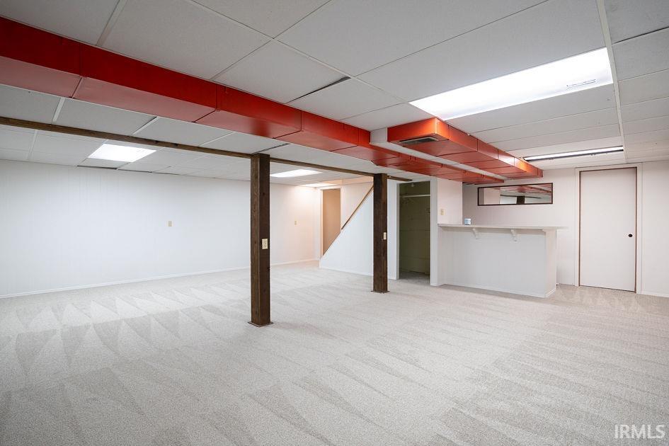 Finished below grade area with light carpet and a paneled ceiling