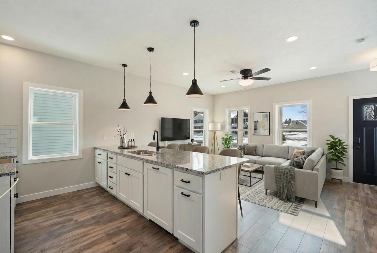 Kitchen with white cabinetry, light stone counters, a peninsula, pendant lighting, and dark wood-style flooring