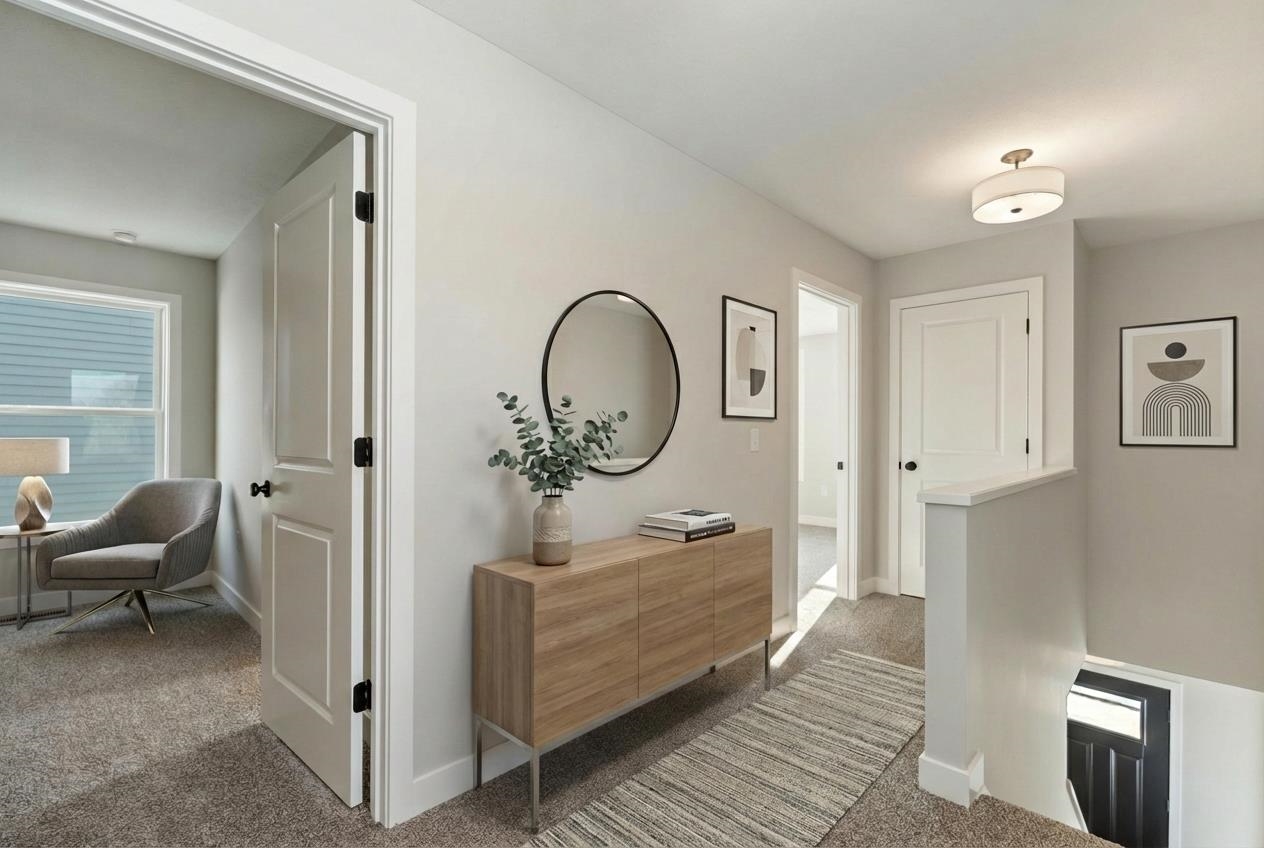 Hallway with dark carpet and an upstairs landing