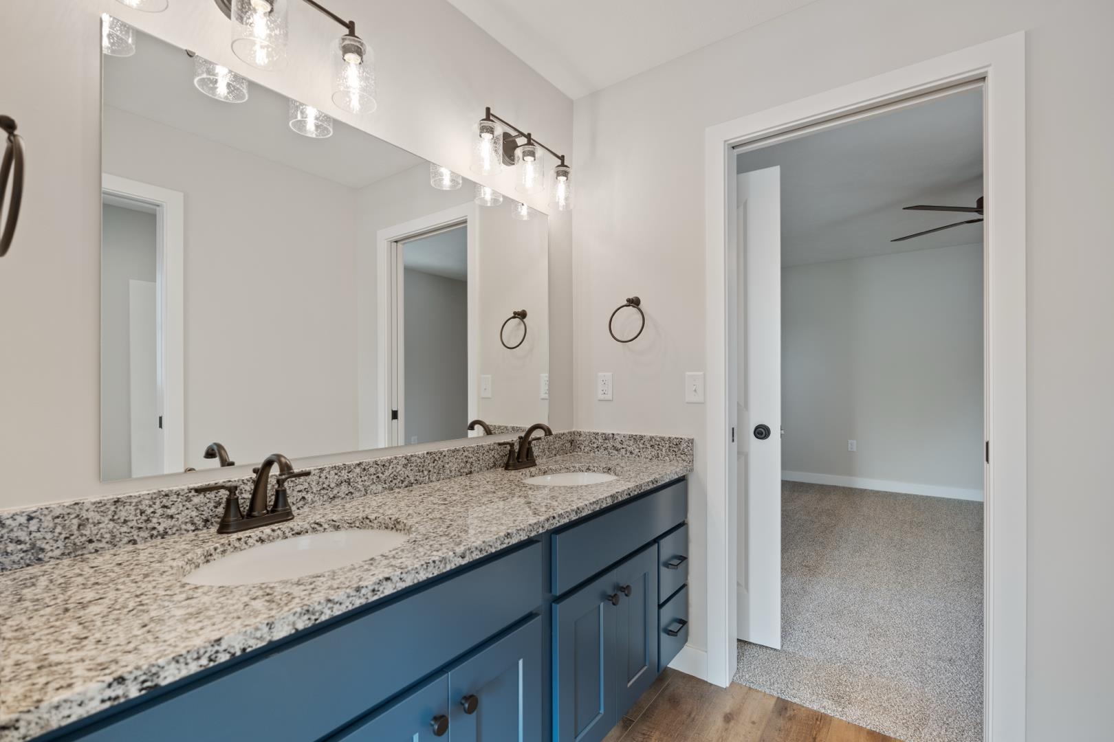 Full bathroom with double vanity, ceiling fan, and light wood-style floors
