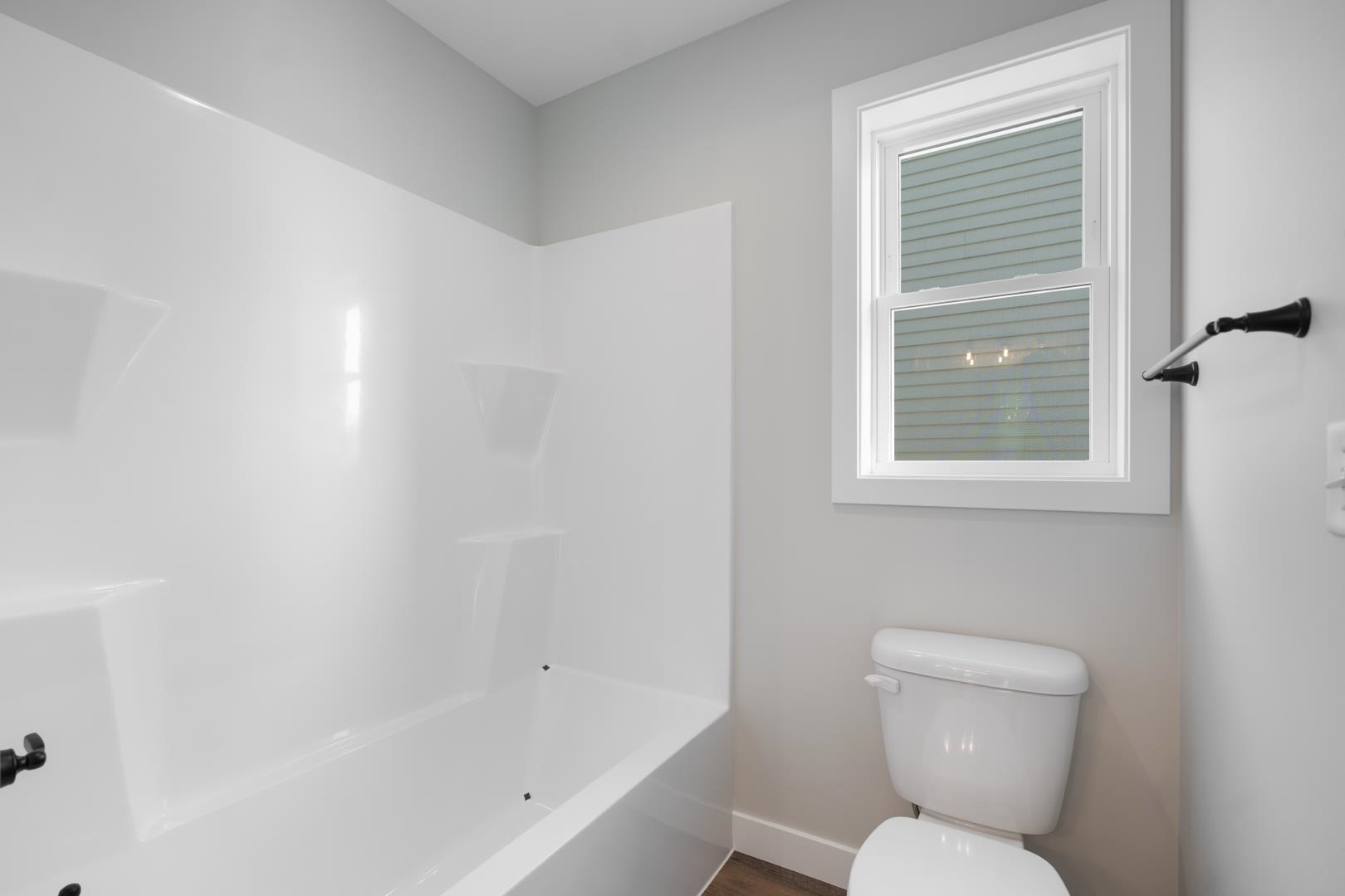 Full bath with shower / bath combination and dark wood-type flooring