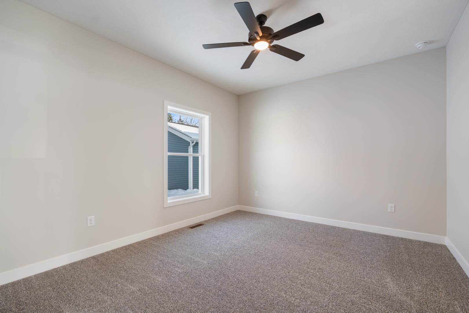 Carpeted empty room featuring baseboards and a ceiling fan