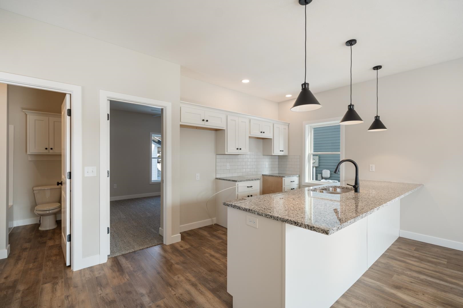 Kitchen with light stone counters, decorative backsplash, a breakfast bar area, a peninsula, and hanging light fixtures