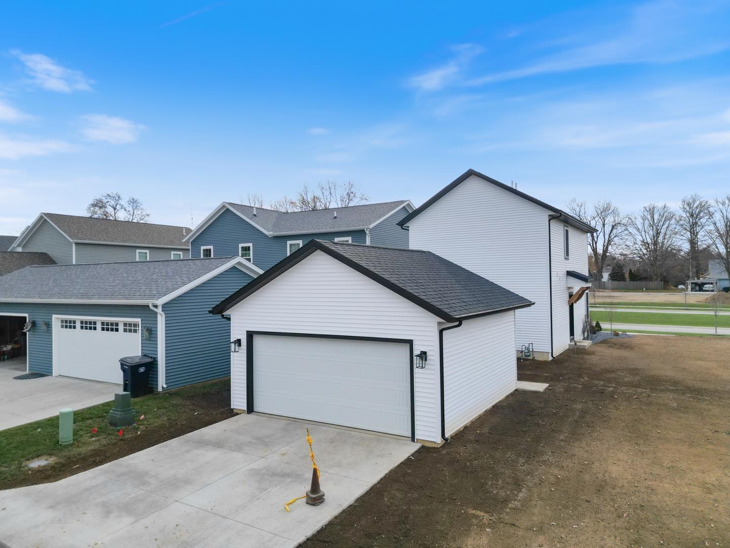 View of front of property with roof with shingles, concrete driveway, an outbuilding, and a garage