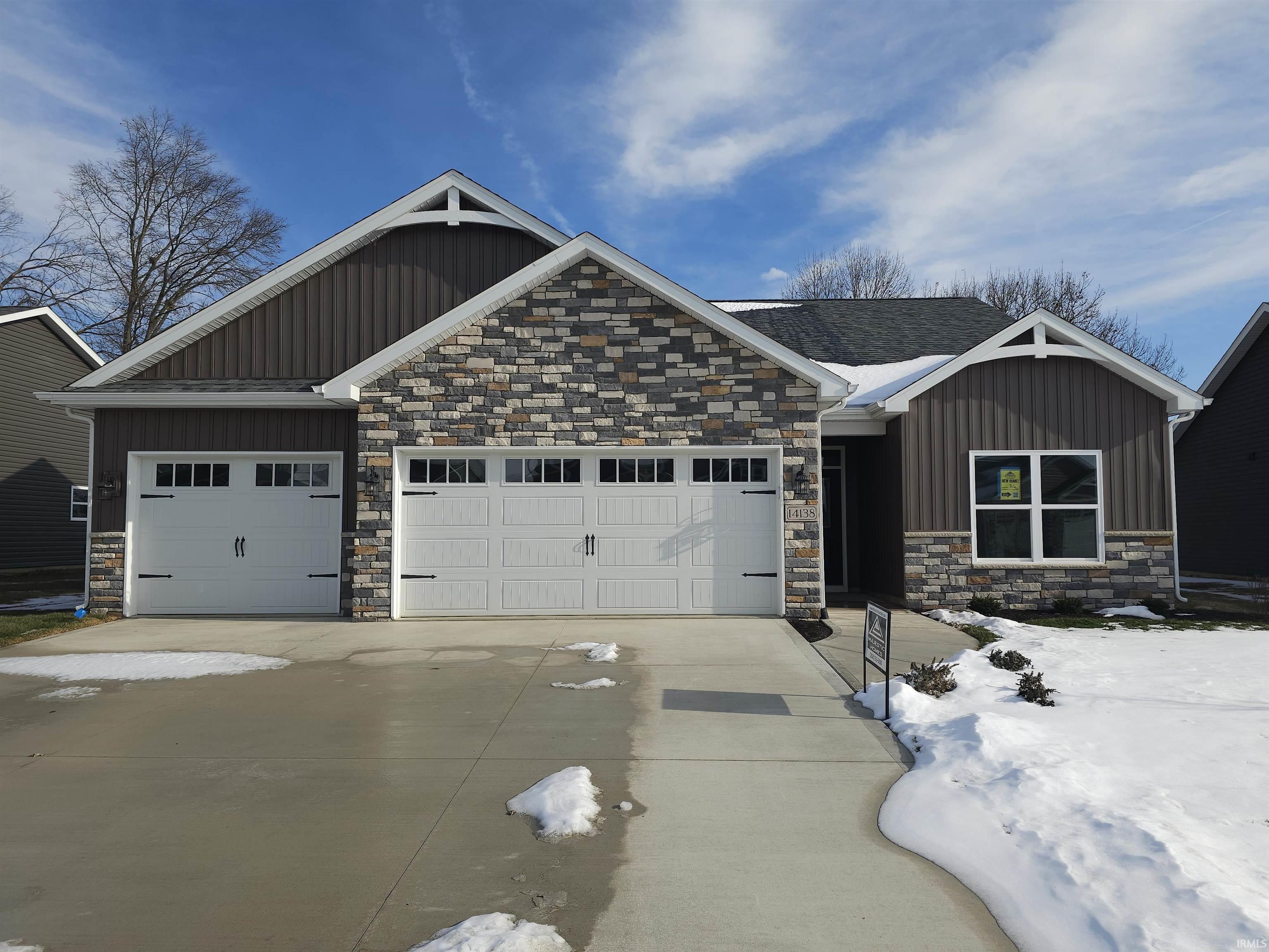 Craftsman-style home with board and batten siding, stone siding, driveway, and a garage