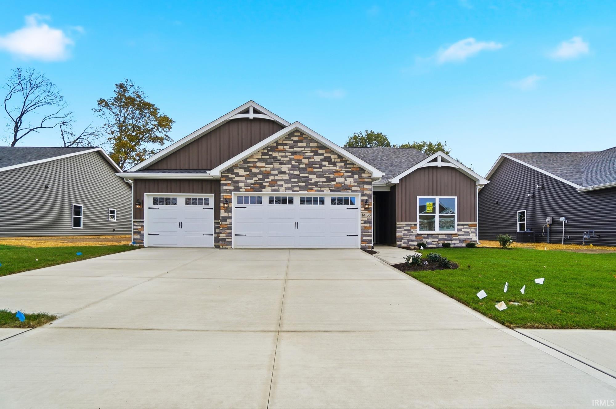 Craftsman house featuring board and batten siding, stone siding, an attached garage, driveway, and a front yard