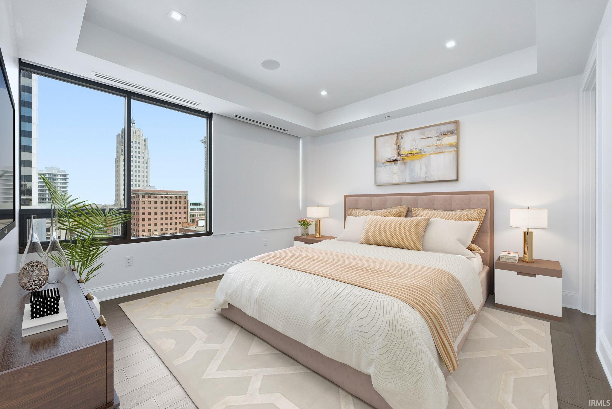 Bedroom featuring a raised ceiling, wood finished floors, and recessed lighting