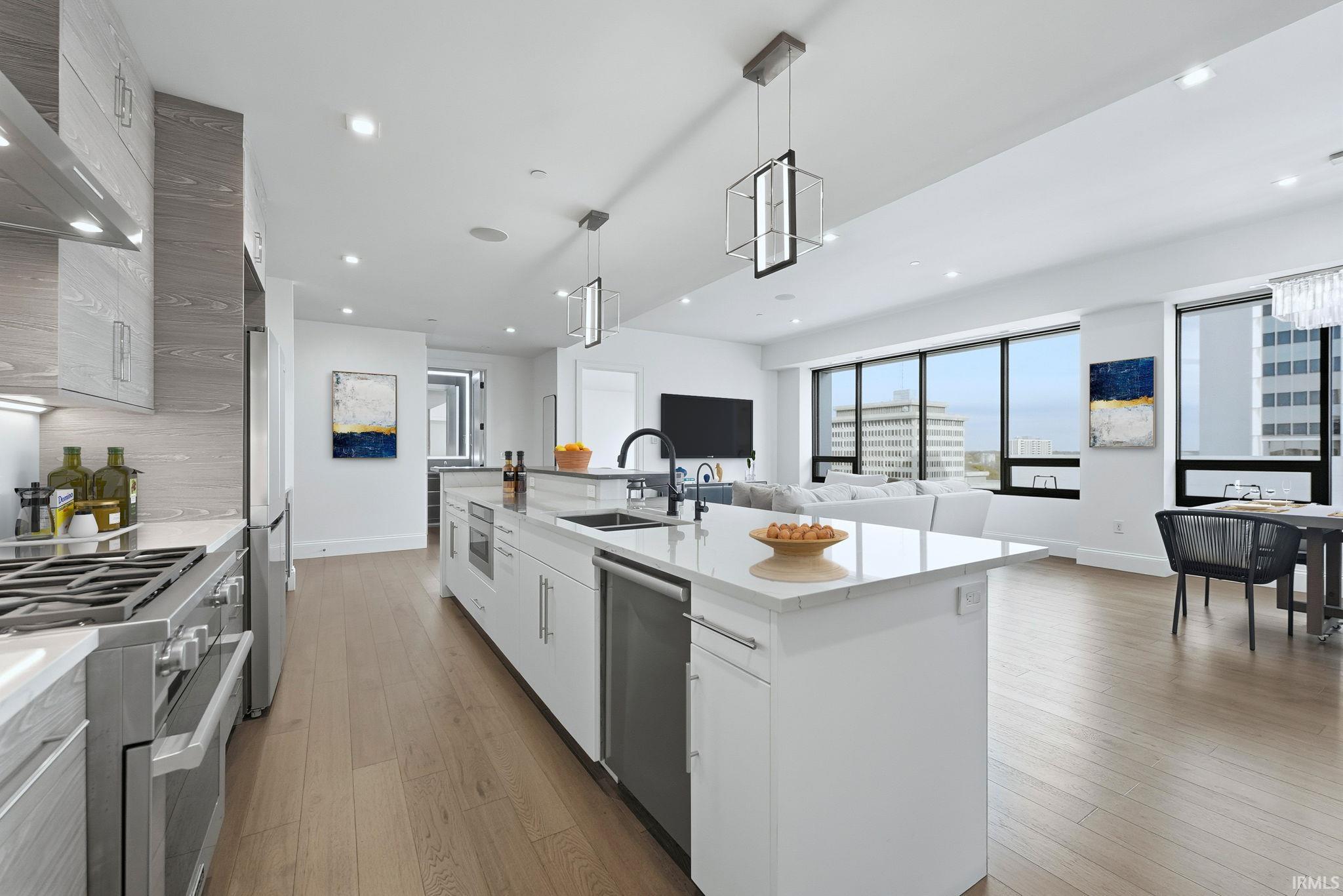 Kitchen with light stone countertops, appliances with stainless steel finishes, hanging light fixtures, white cabinets, and recessed lighting