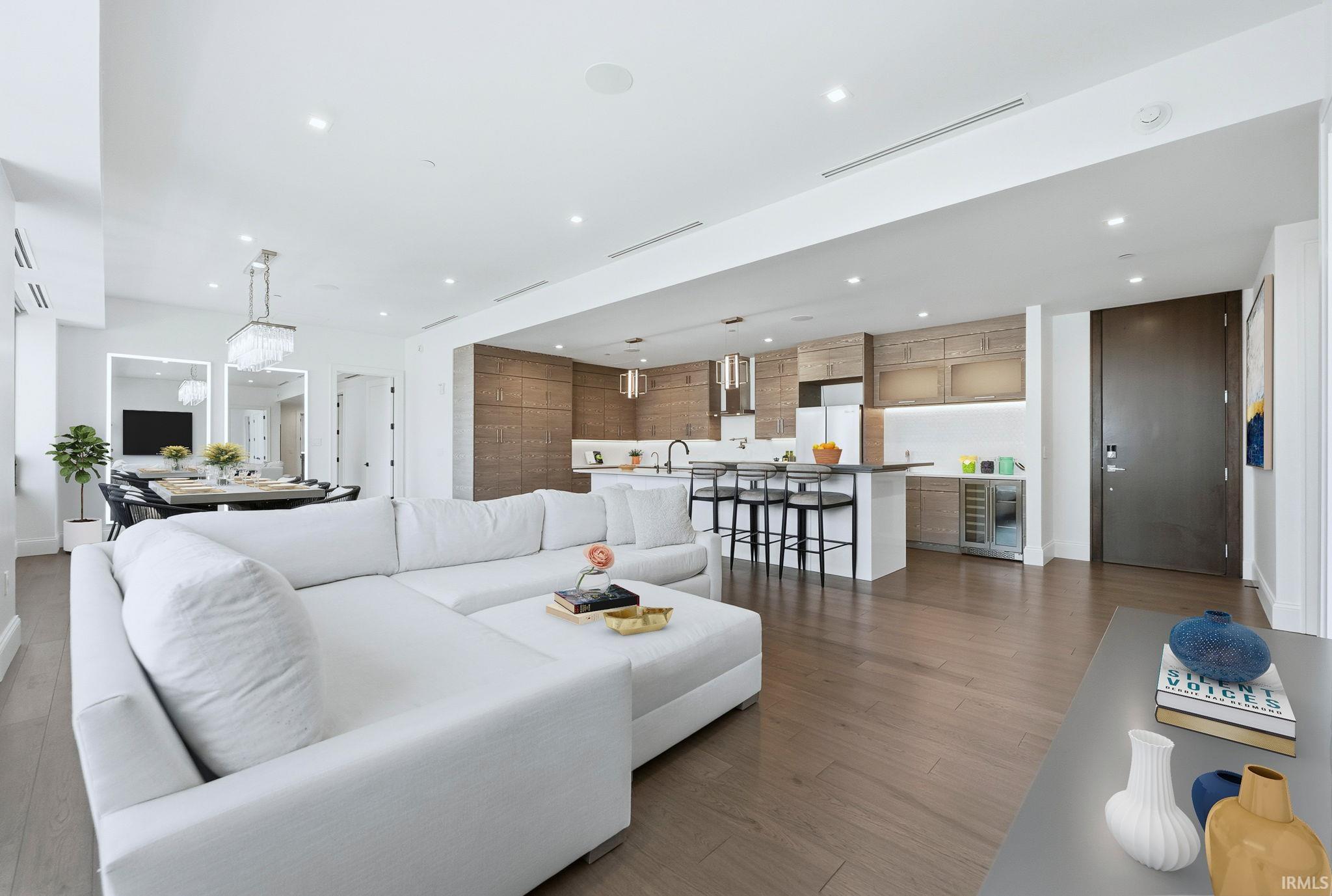 Living room with dark wood finished floors, recessed lighting, and beverage cooler