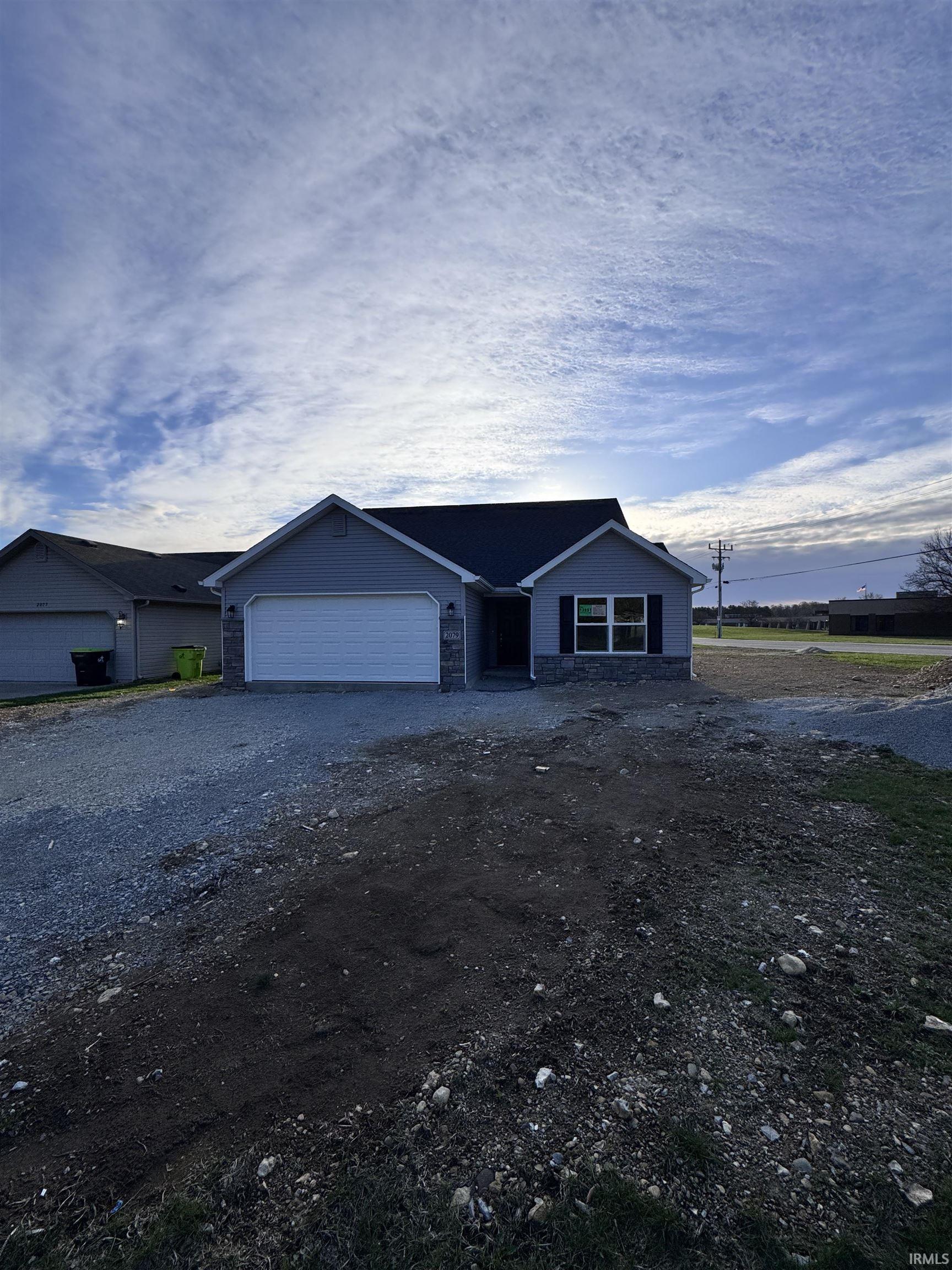 Single story home with driveway, an attached garage, and stone siding