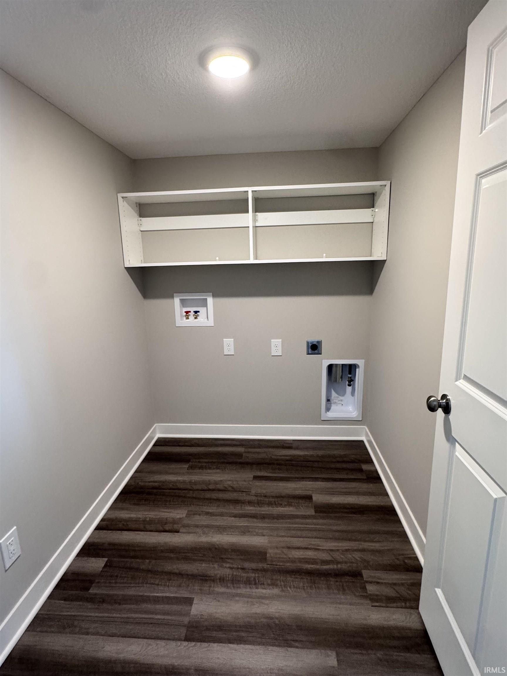 Laundry room featuring electric dryer hookup, hookup for a washing machine, dark wood-style floors, and a textured ceiling