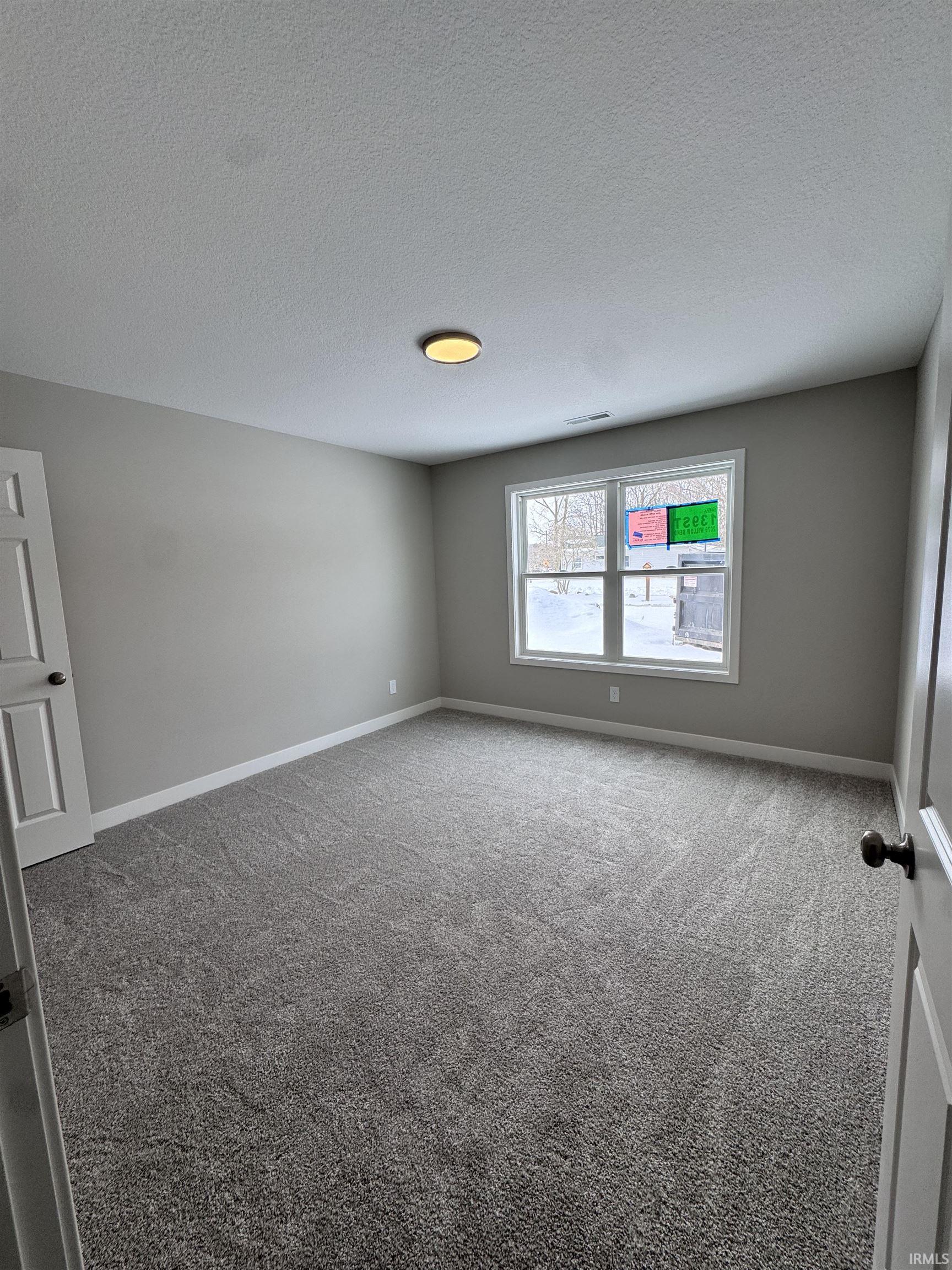 Carpeted empty room with baseboards and a textured ceiling