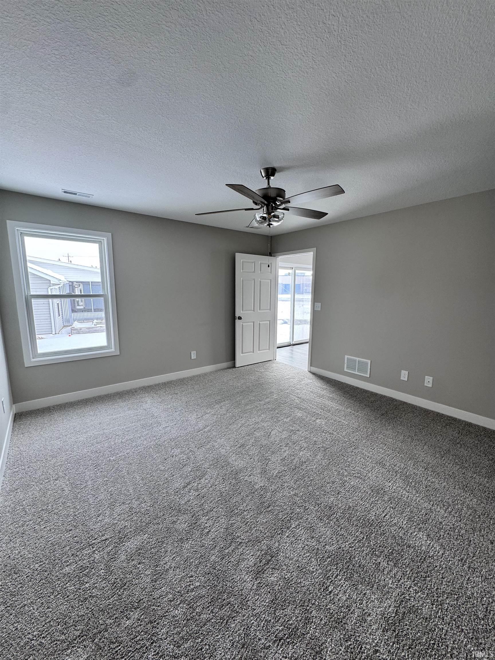 Unfurnished room with a ceiling fan, carpet flooring, and a textured ceiling