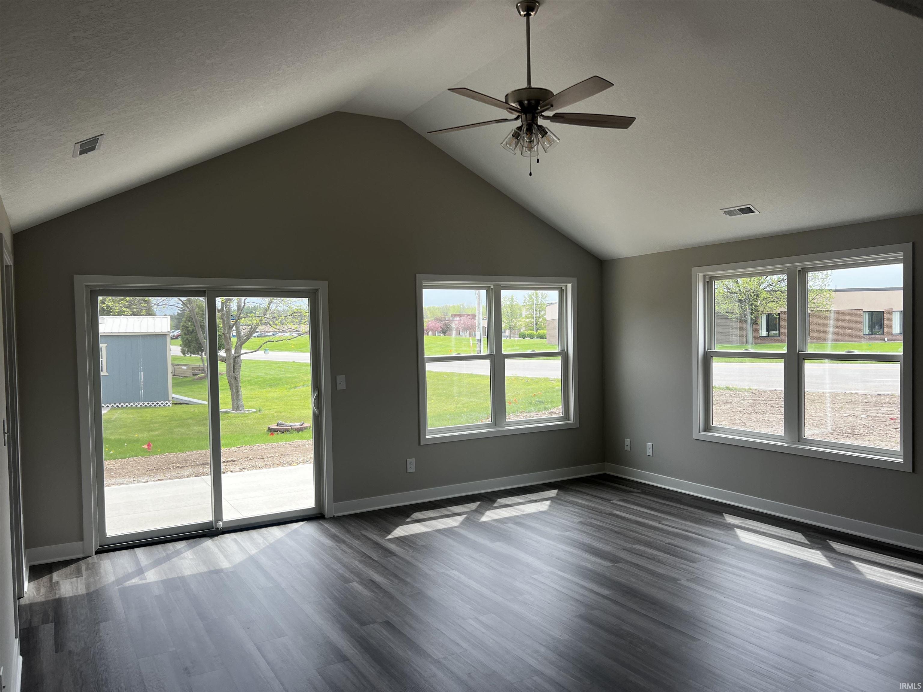 Unfurnished living room with ceiling fan, healthy amount of natural light, and dark wood finished floors