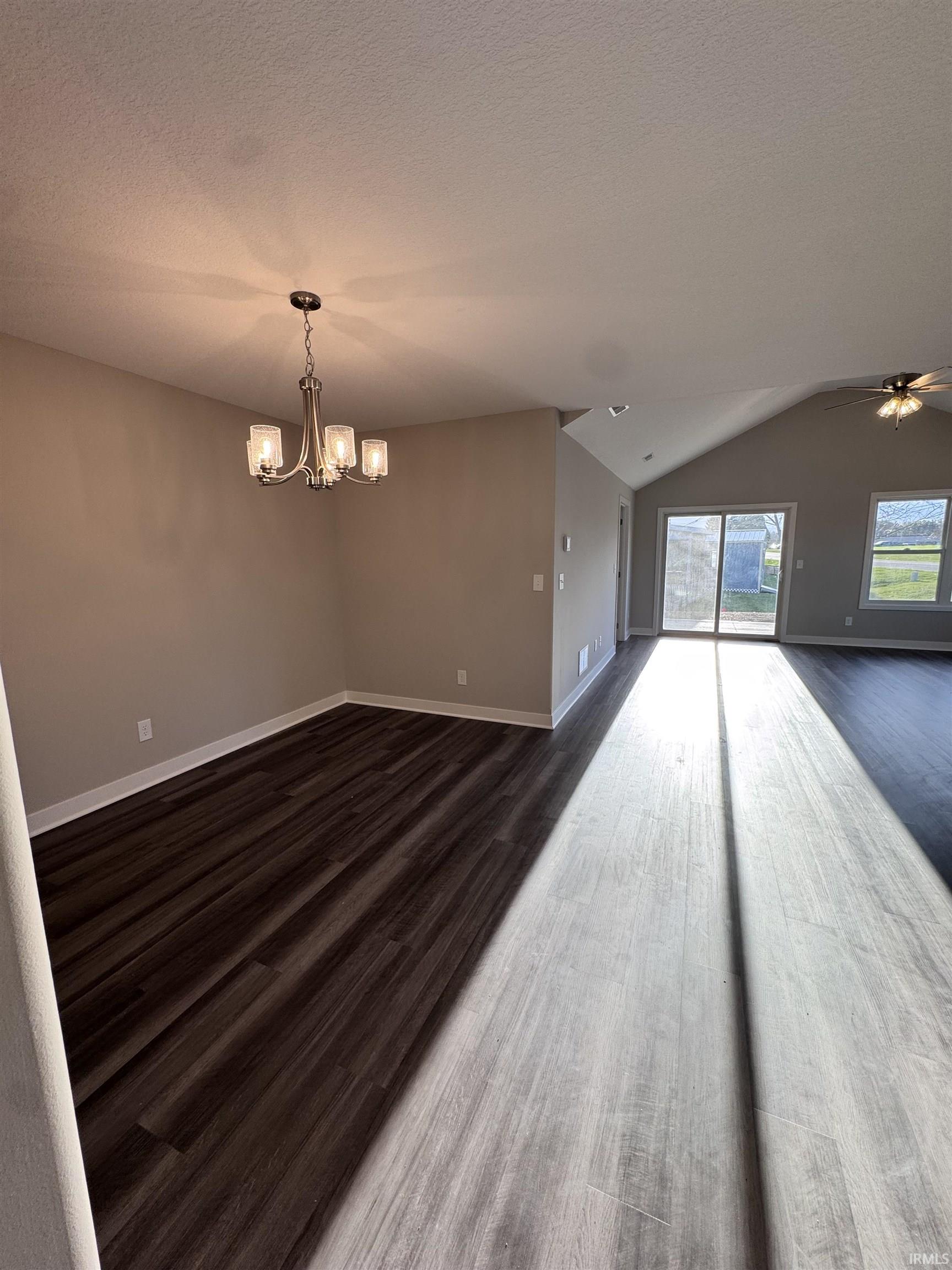 Unfurnished dining area featuring dark wood-style flooring, hanging lights, and a ceiling fan