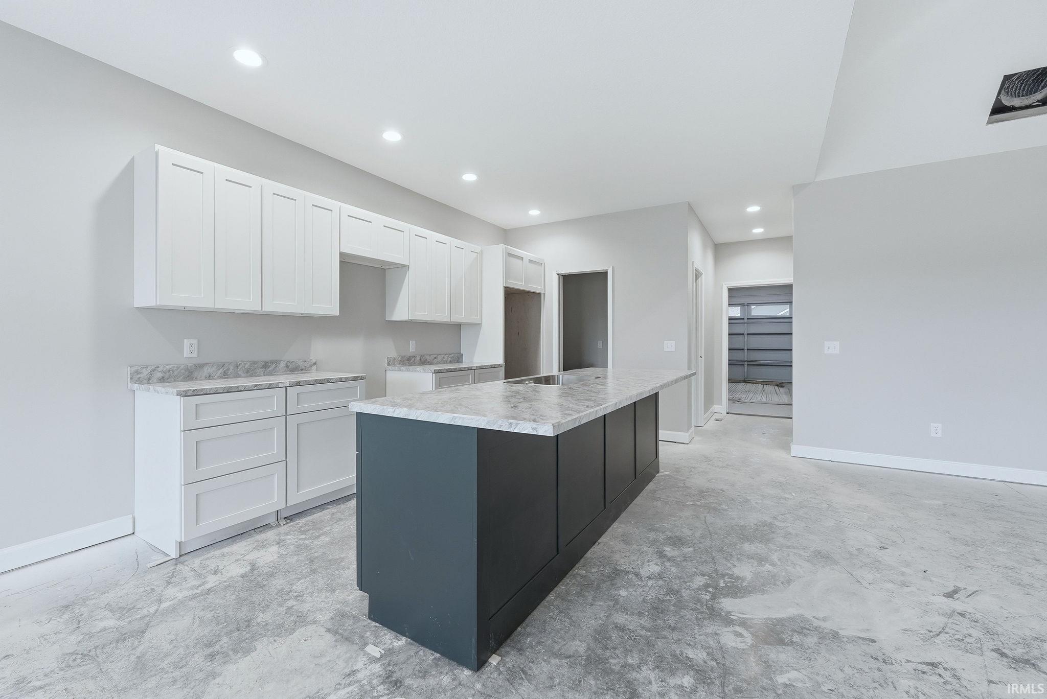 Dual tone kitchen featuring an island with sink, unfinished concrete floors, dual tone cabinetry, and recessed lighting