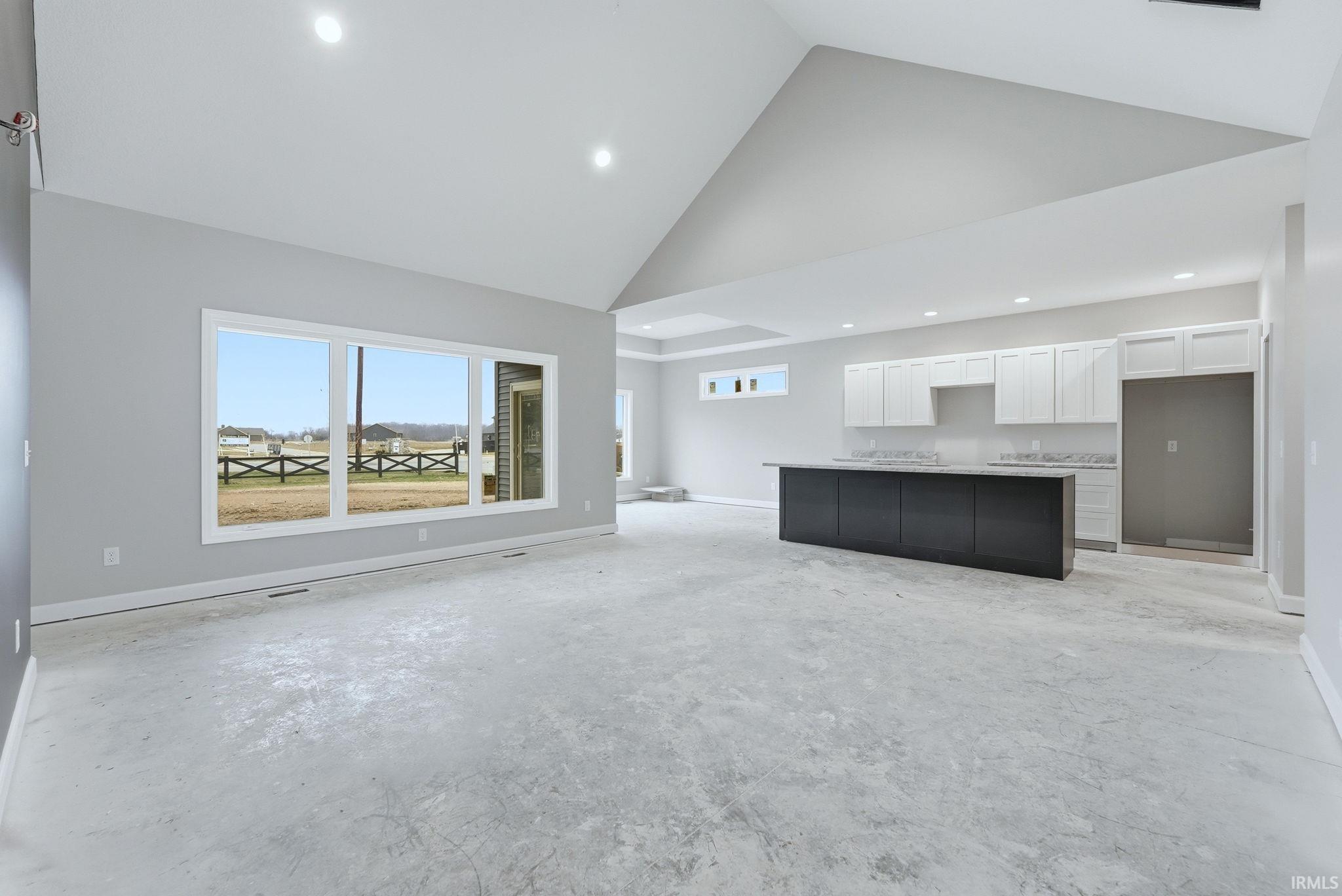 Unfurnished living room with unfinished concrete flooring, recessed lighting, and vaulted ceiling