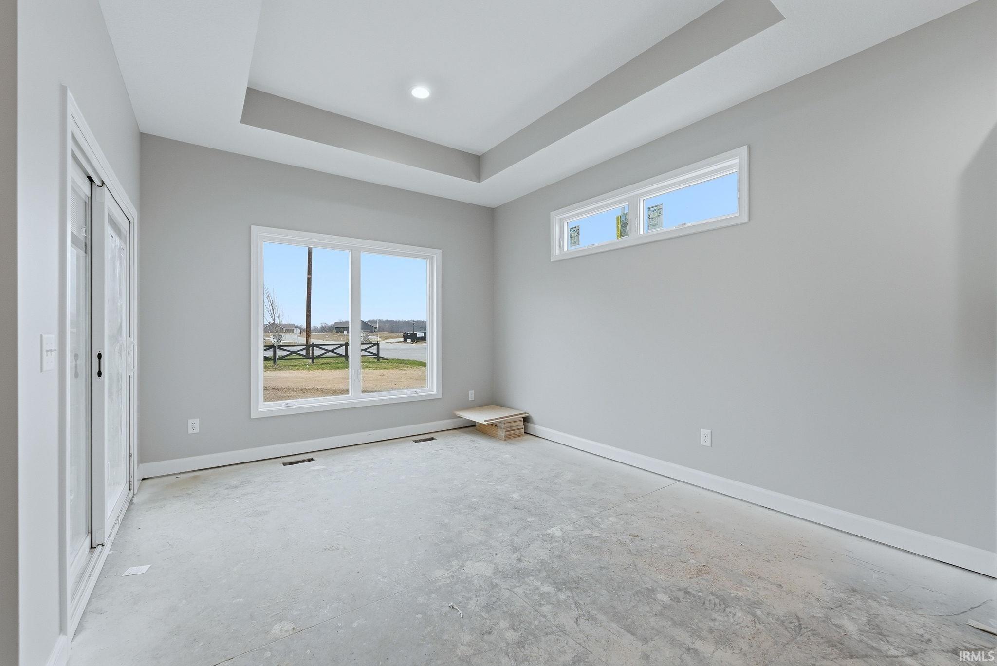 Unfurnished bedroom with a tray ceiling and multiple windows