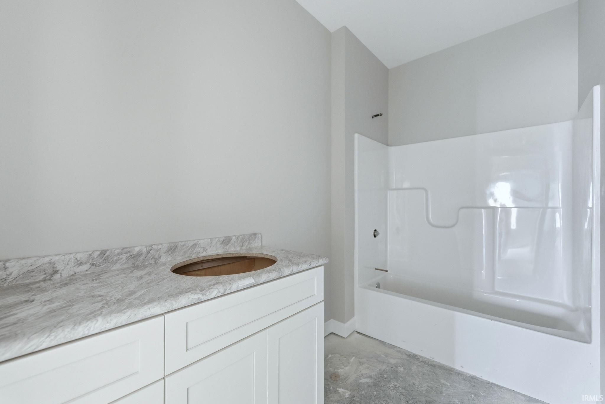 Bathroom featuring vanity, concrete floors, and bathtub / shower combination