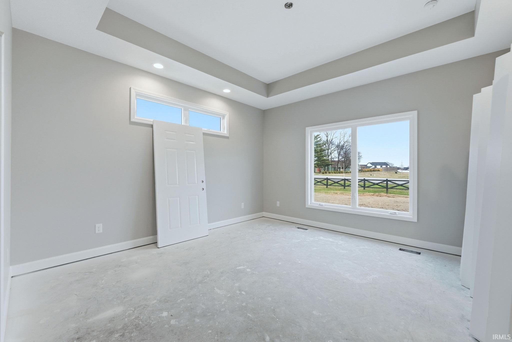 Empty room featuring a tray ceiling and plenty of natural light