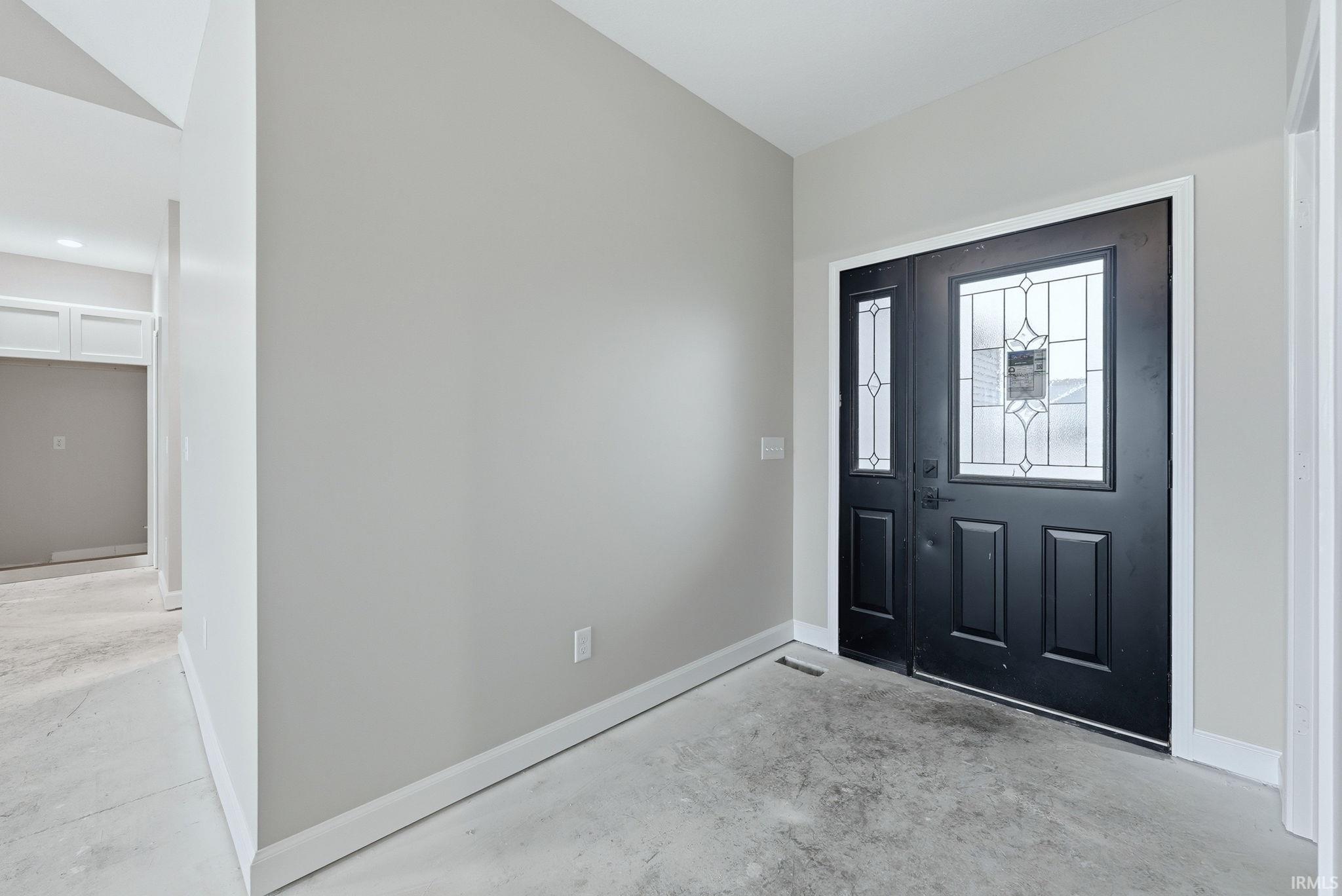 Foyer with concrete flooring and baseboards