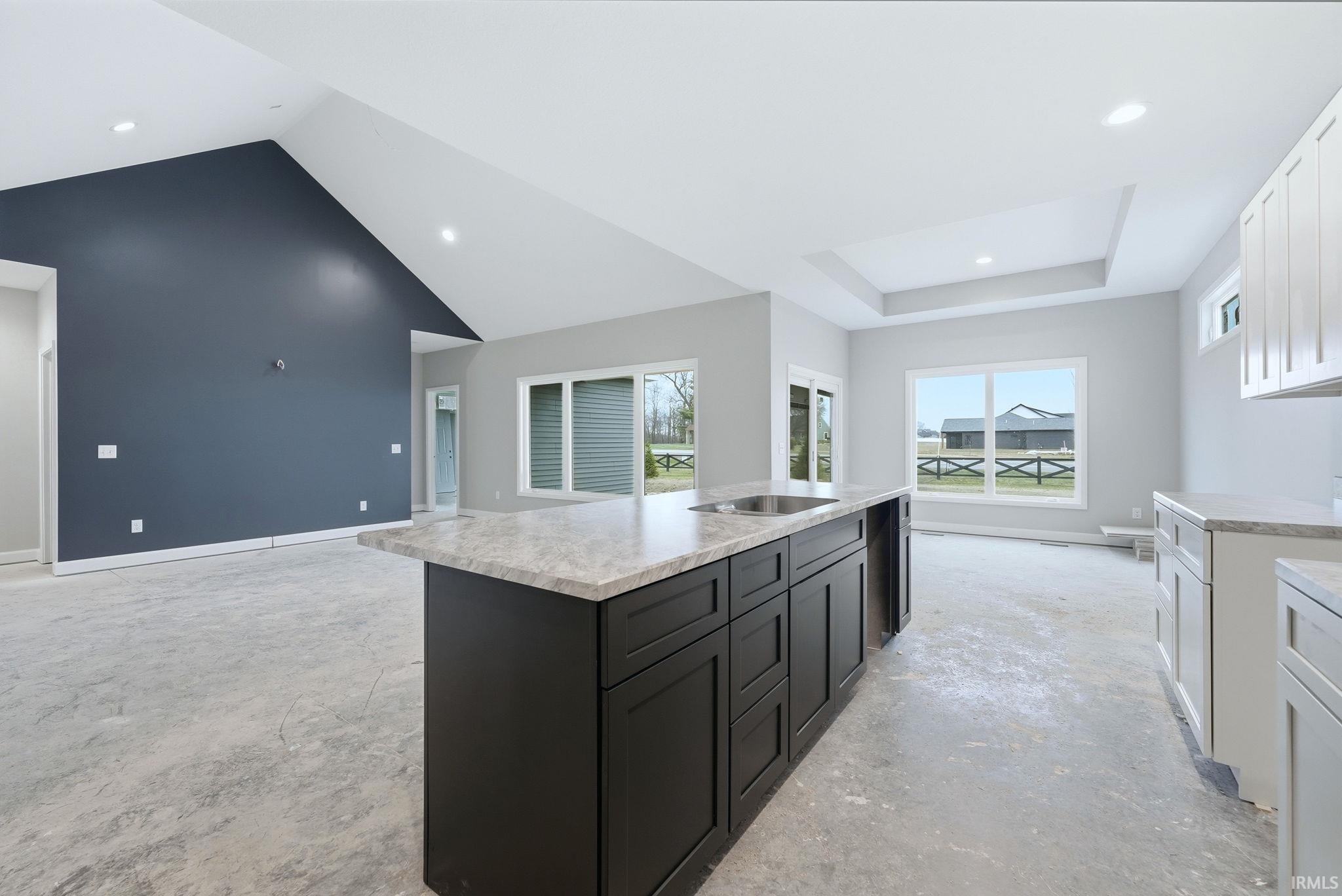 Kitchen with concrete floors, an island with sink, open floor plan, white cabinetry, and recessed lighting