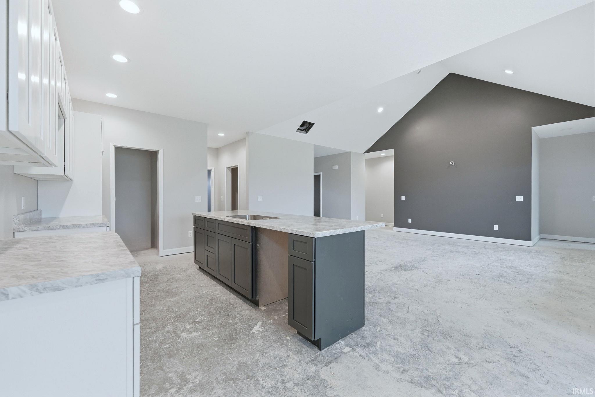 Kitchen featuring a center island with sink, concrete floors, recessed lighting, two tone cabinetry, and open floor plan