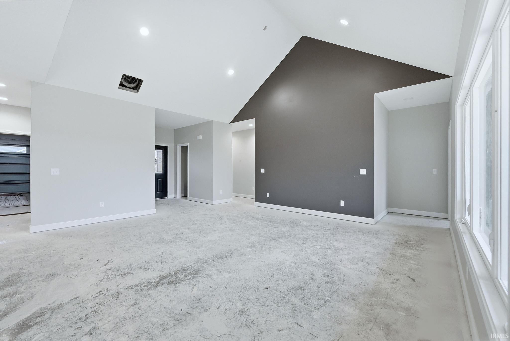 Unfurnished living room with a high ceiling and recessed lighting