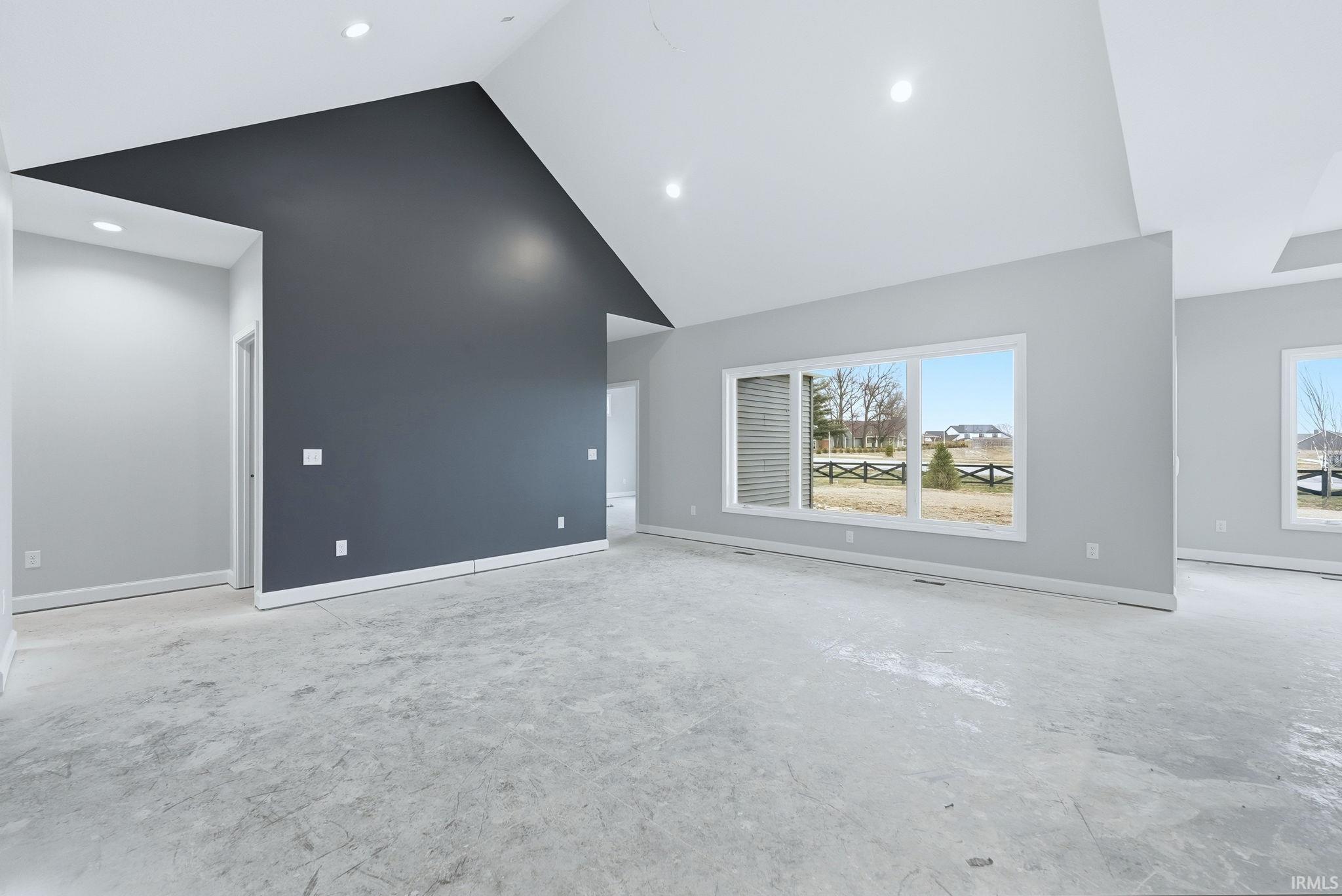 Unfurnished living room featuring a high ceiling, recessed lighting, and concrete floors