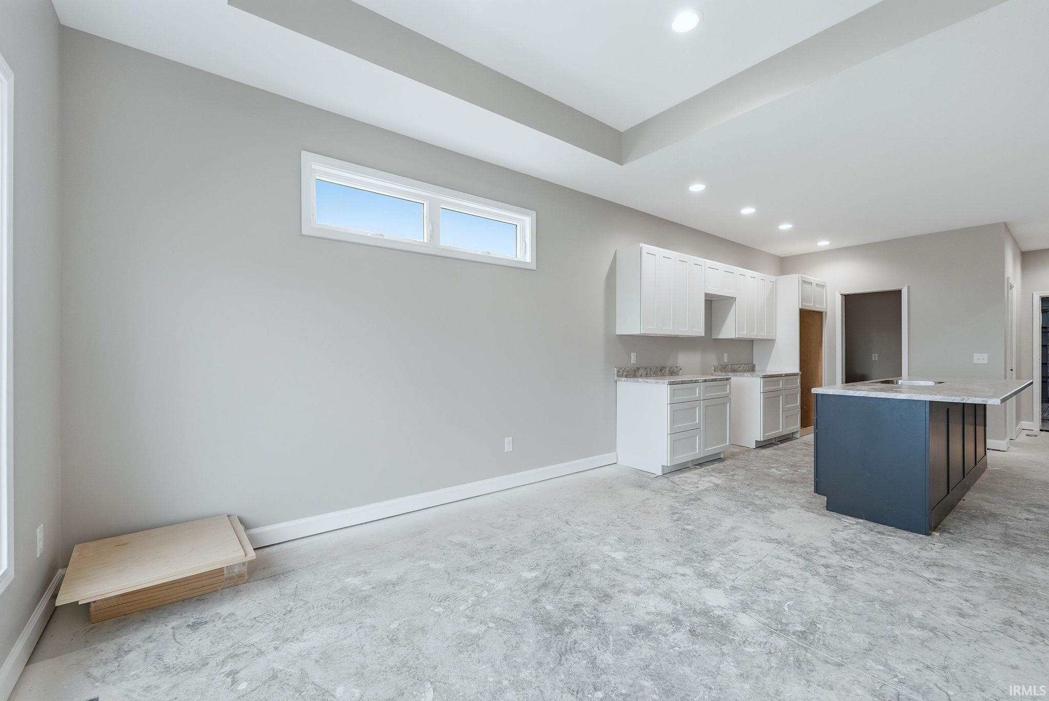 Kitchen with a kitchen island, two tone color scheme, recessed lighting, and light stone counters