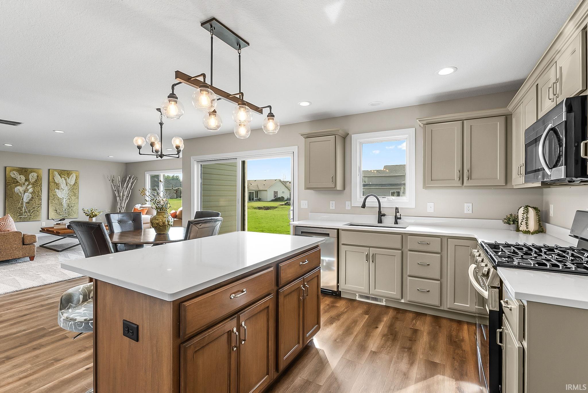 Kitchen with stainless steel appliances, a center island, open floor plan, dark wood-style flooring, and two tone cabinetry