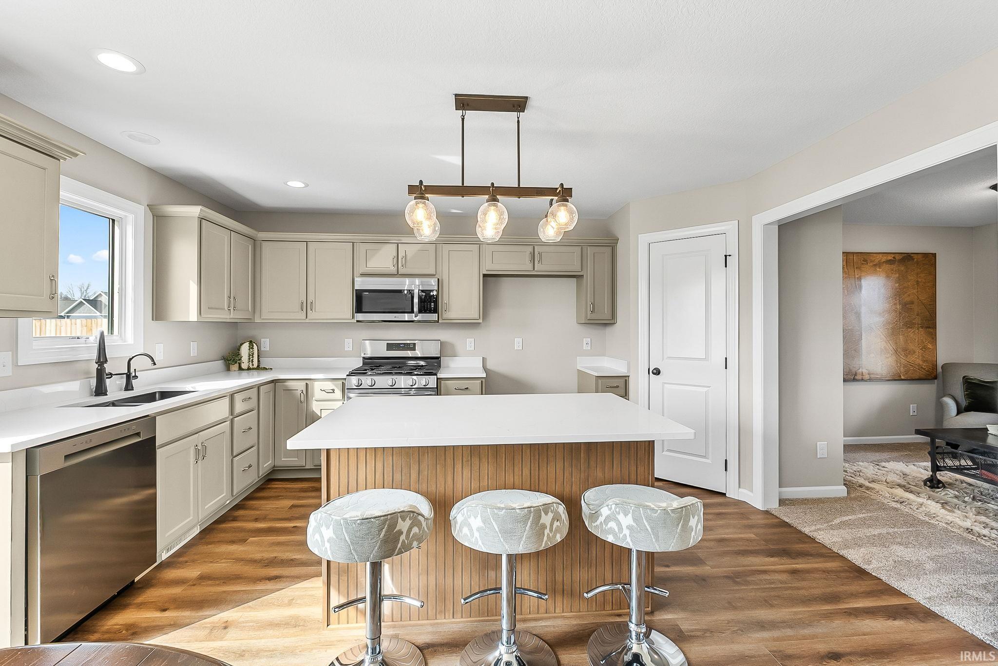 Kitchen with a kitchen island, stainless steel appliances, light wood-type flooring, a breakfast bar area, and pendant lighting