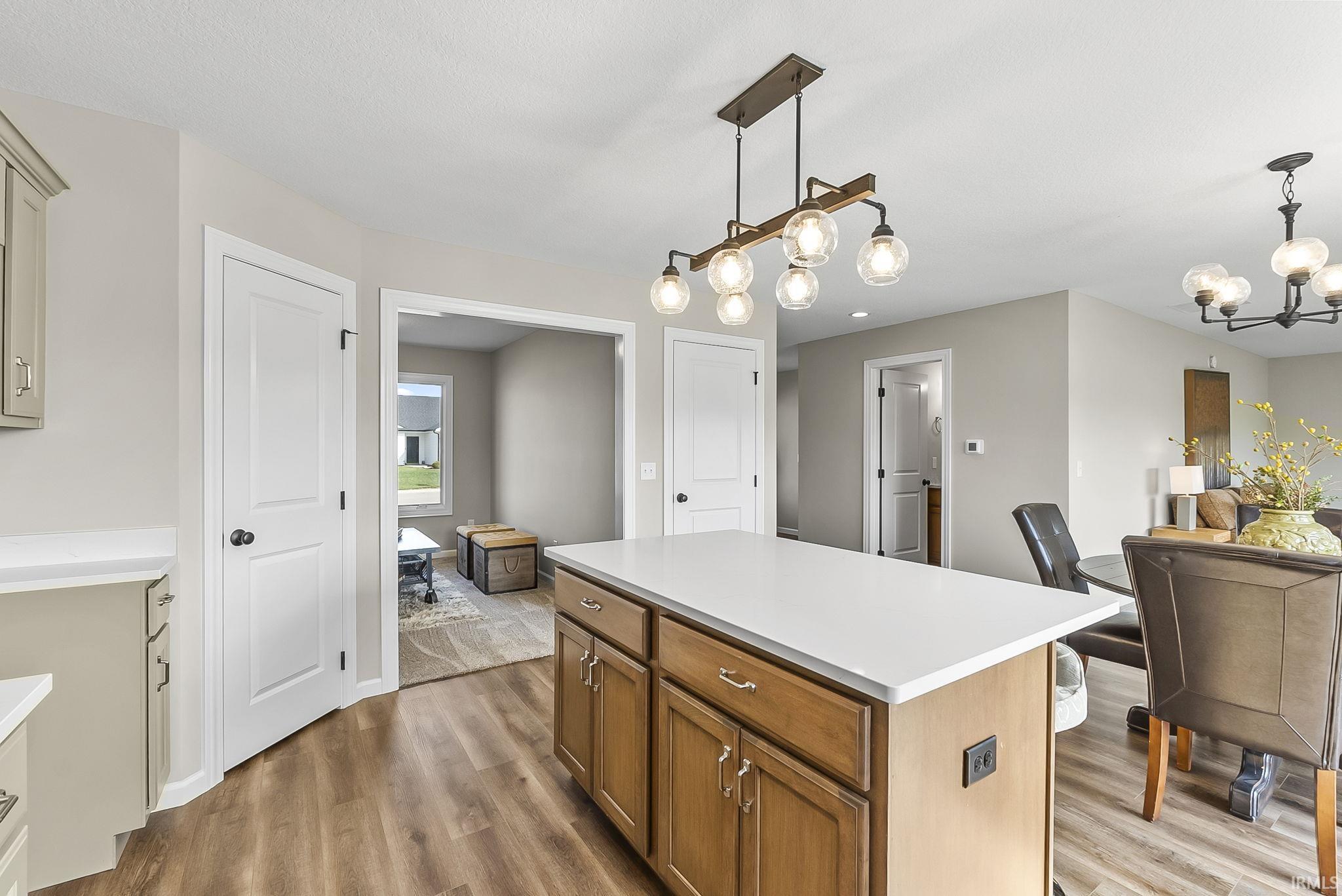 Kitchen featuring a center island, light countertops, wood finished floors, hanging lights, and wood finish cabinetry