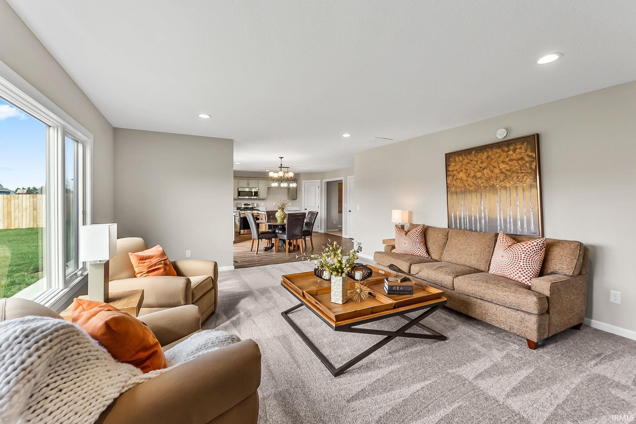 Living room with light colored carpet and suspended lighting