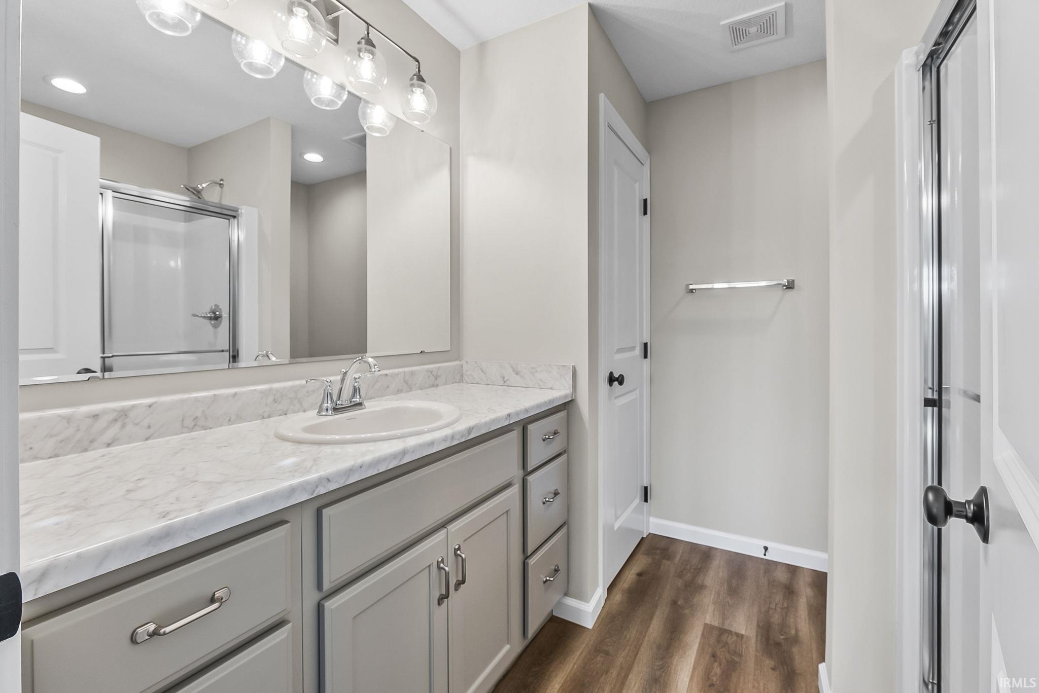 Bathroom with vanity, dark wood-style flooring, and a stall shower